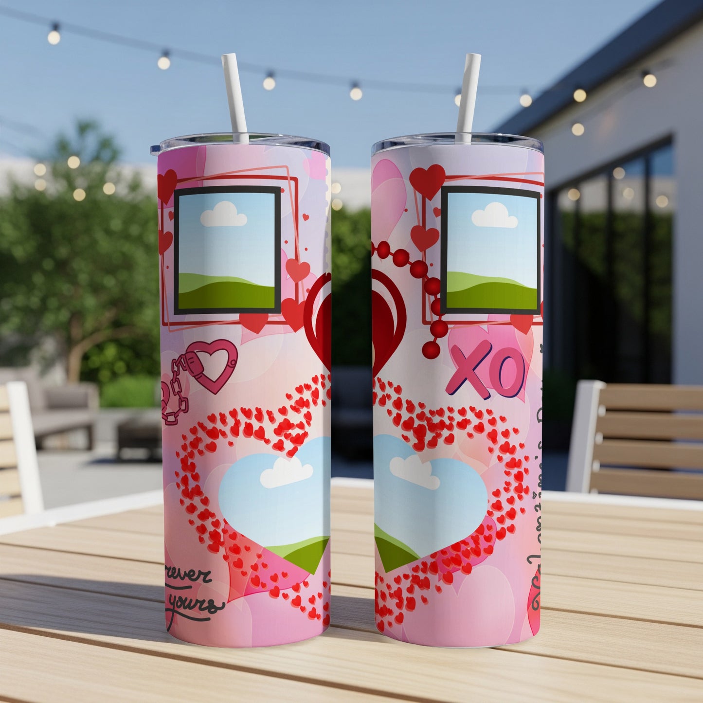 Two pink tumblers with hearts, clouds, and photo frames displayed outdoors.