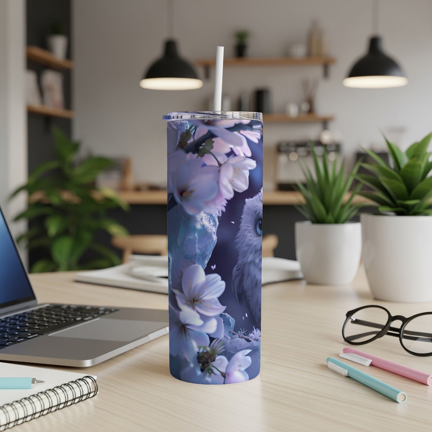 Blue tumbler with owl and cherry blossoms design on a desk.