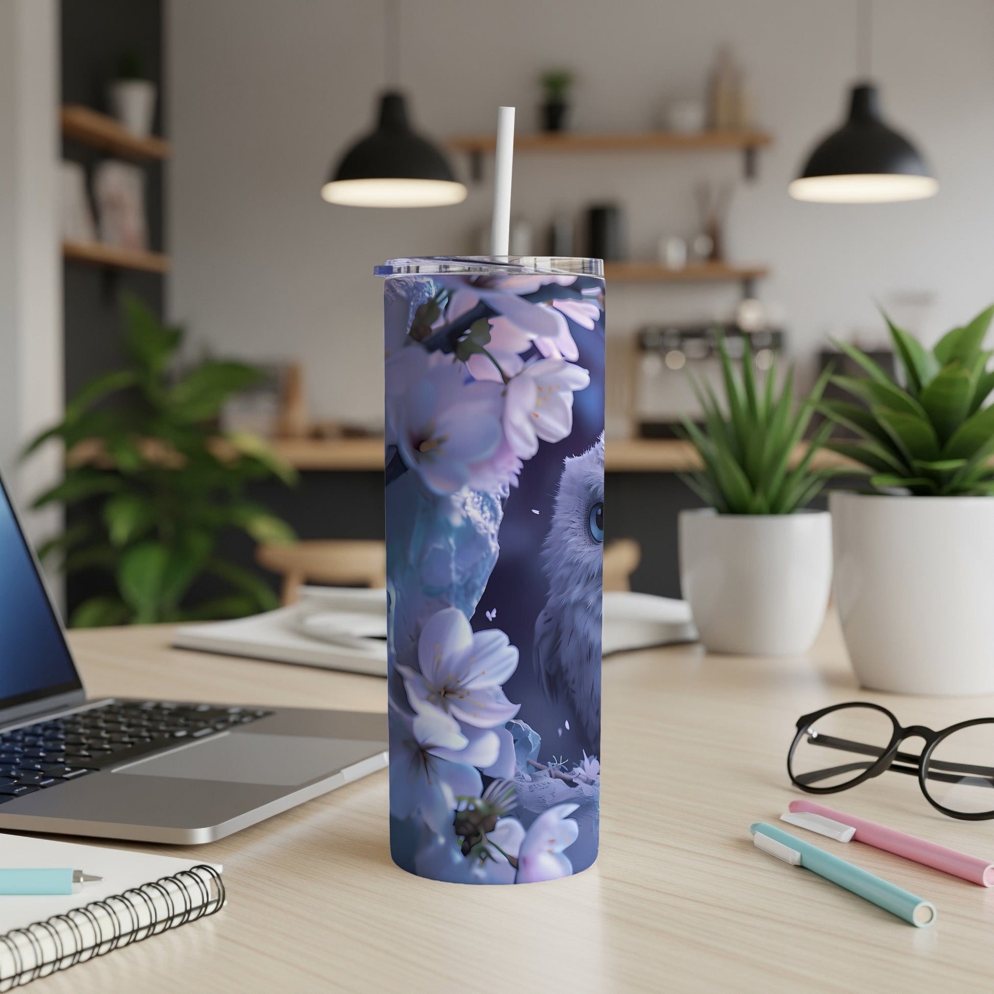 Blue tumbler with owl and cherry blossoms design on a desk.