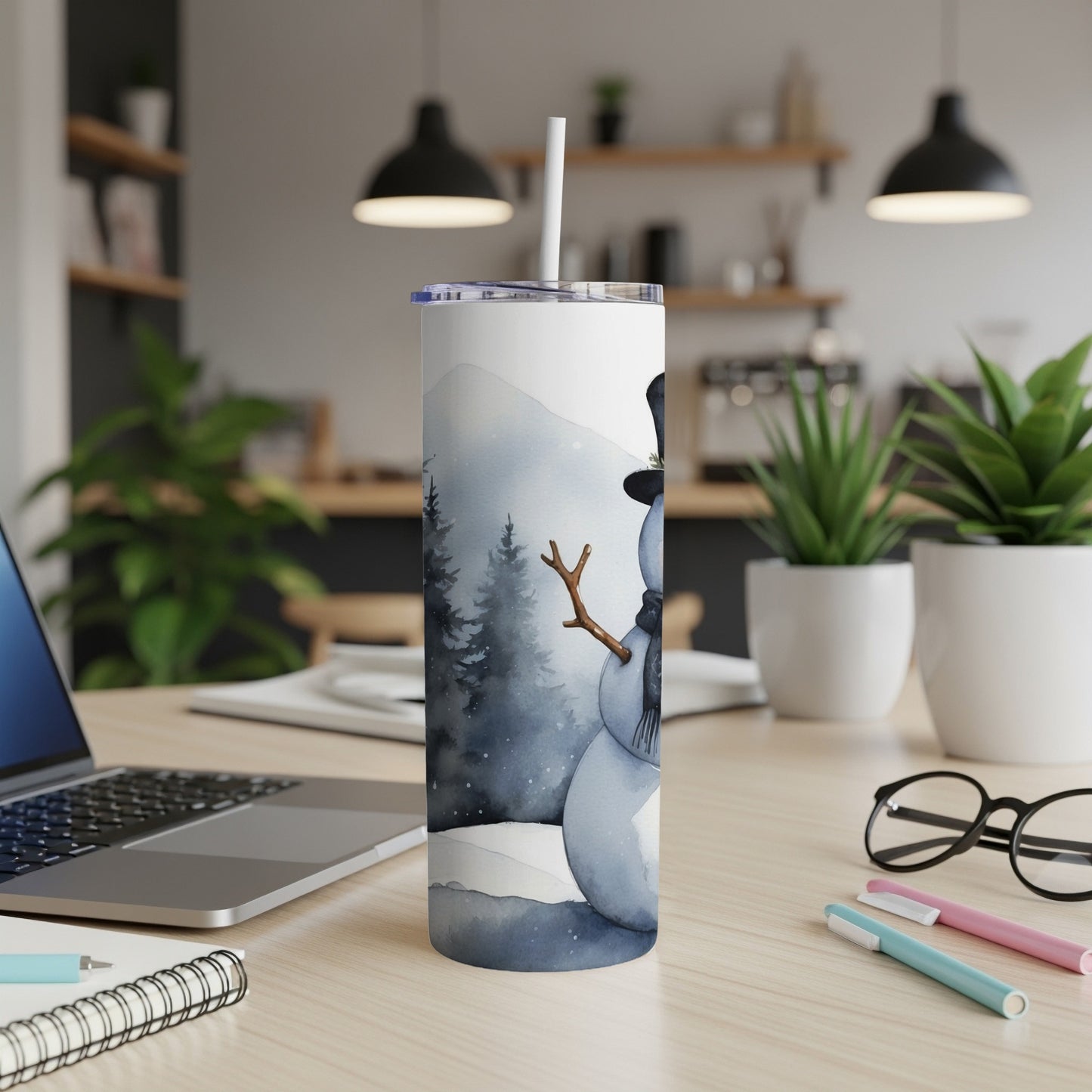 White tumbler with watercolor snowman design on desk.