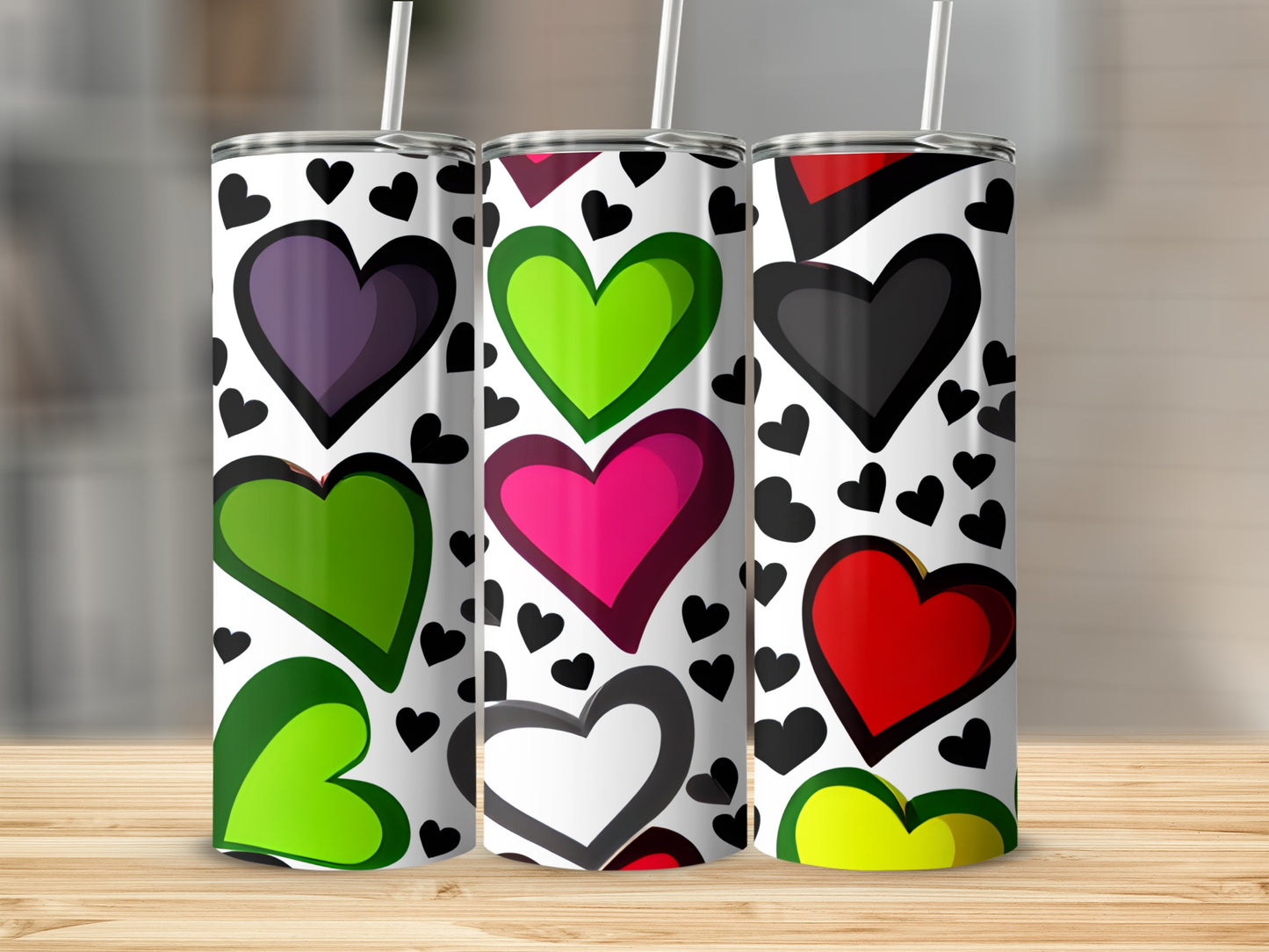 Three tumblers with colorful heart patterns and straws, on a wooden surface.