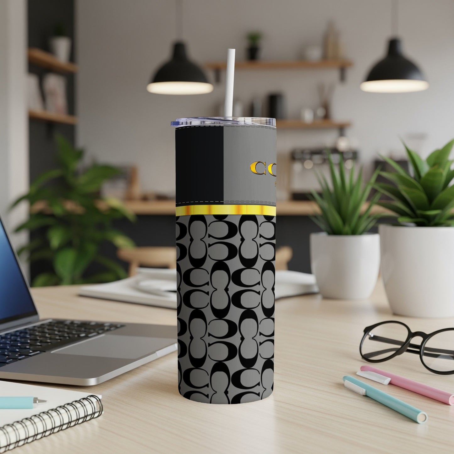 A grey tumbler with an all-over black C logo pattern and gold accents.