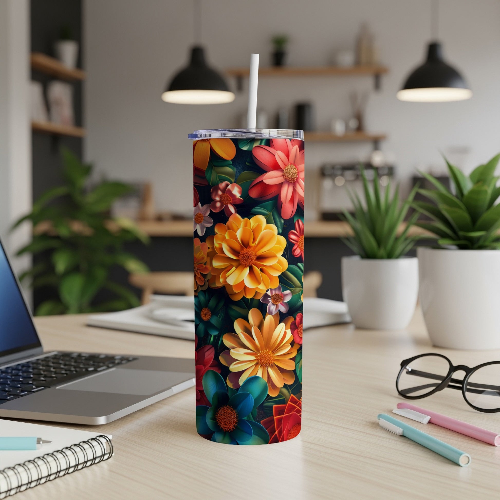 Tall tumbler with vibrant floral pattern and straw on a desk.
