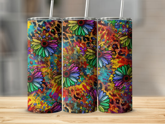 Three tumblers with colorful sunflower and autism puzzle piece designs on a wooden surface.