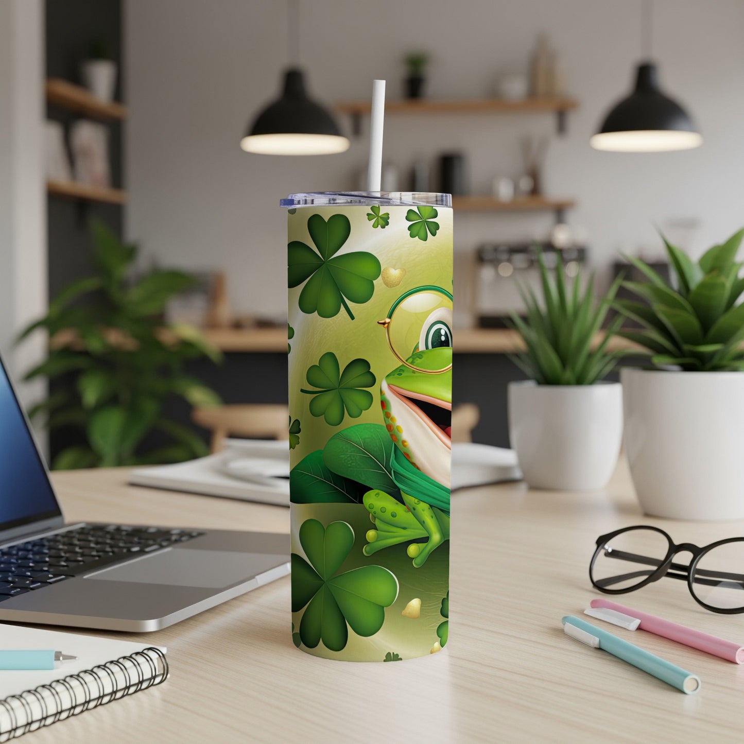 Green tumbler with smiling frog, shamrocks, and straw on a desk.
