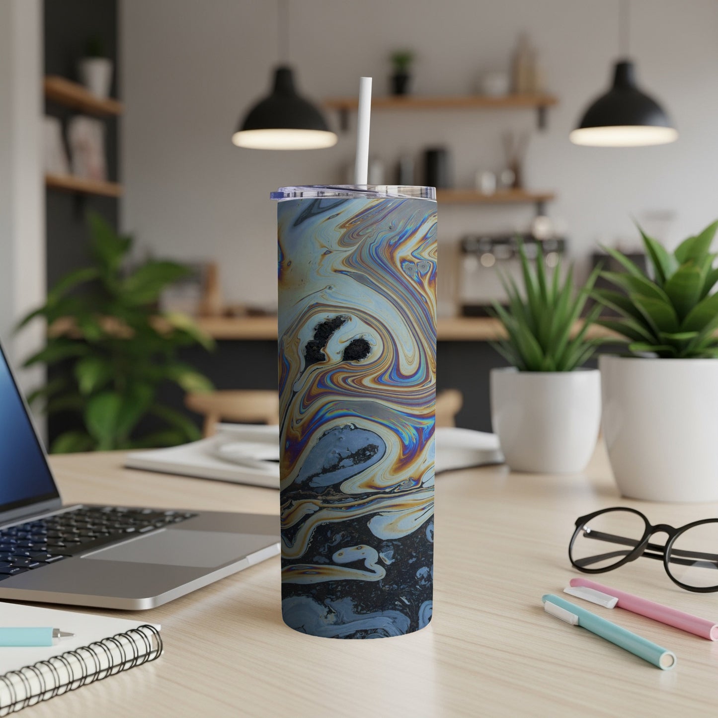 Tumbler with a marbled blue, yellow, and black pattern, on a desk.