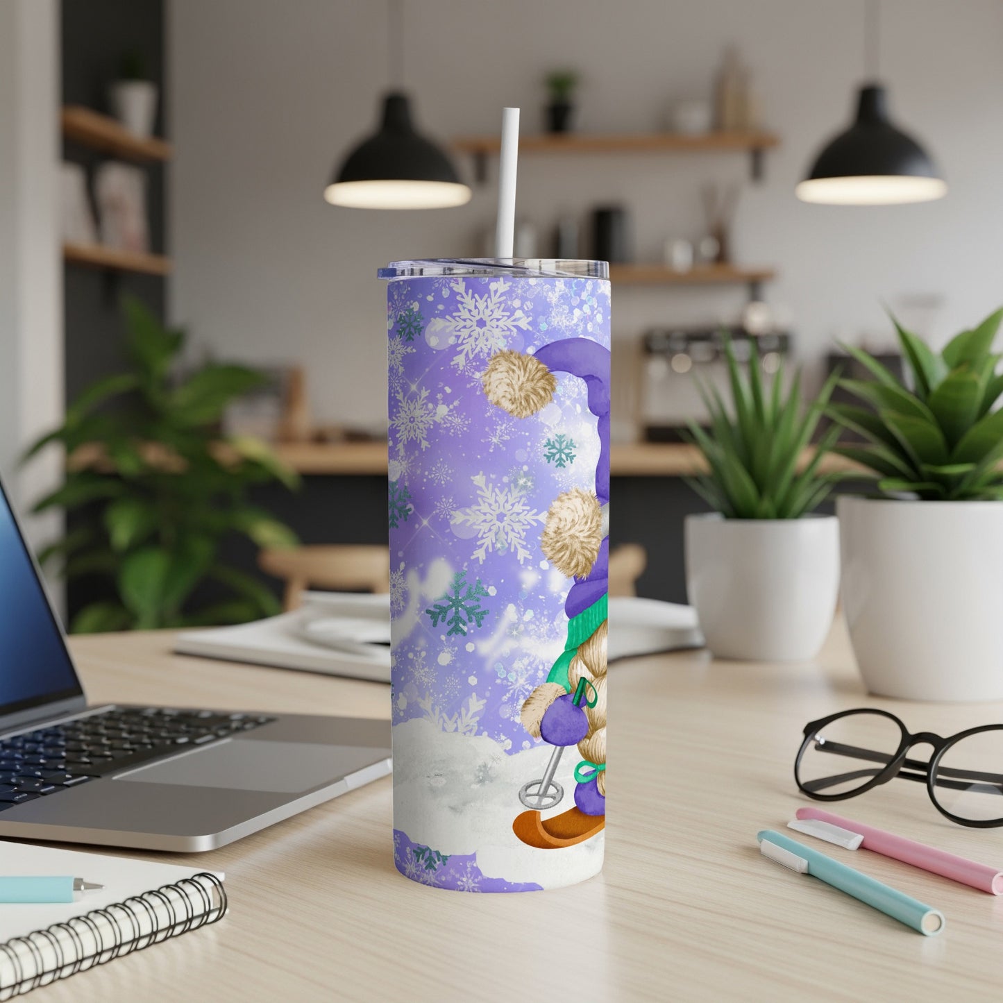 Purple tumbler with snowflakes and gnome artwork on a desk.