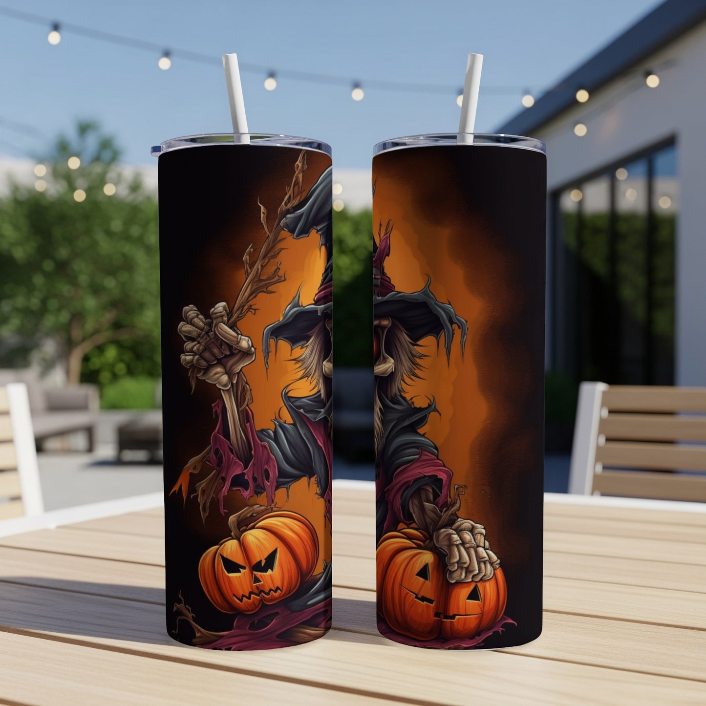 Two tumblers with Halloween scarecrow and pumpkin designs sit on a table outdoors.