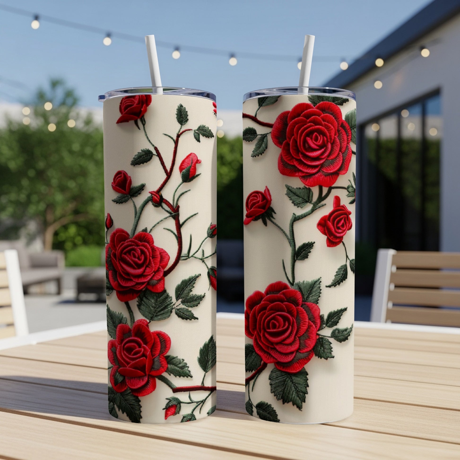 Two cream tumblers with red rose and vine pattern, outdoors.