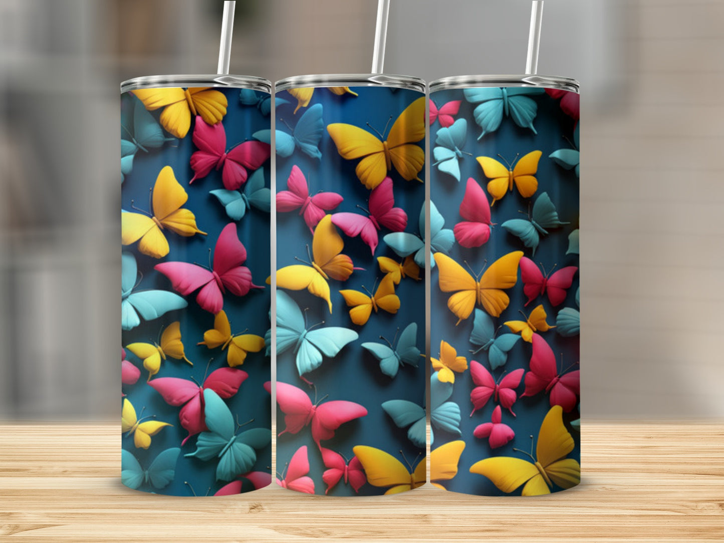 Three tumblers with colorful butterfly designs on a wooden surface.