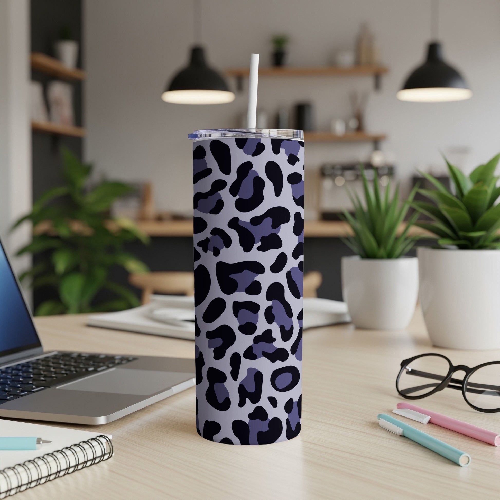 Purple and black leopard print insulated tumbler with straw on a desk.
