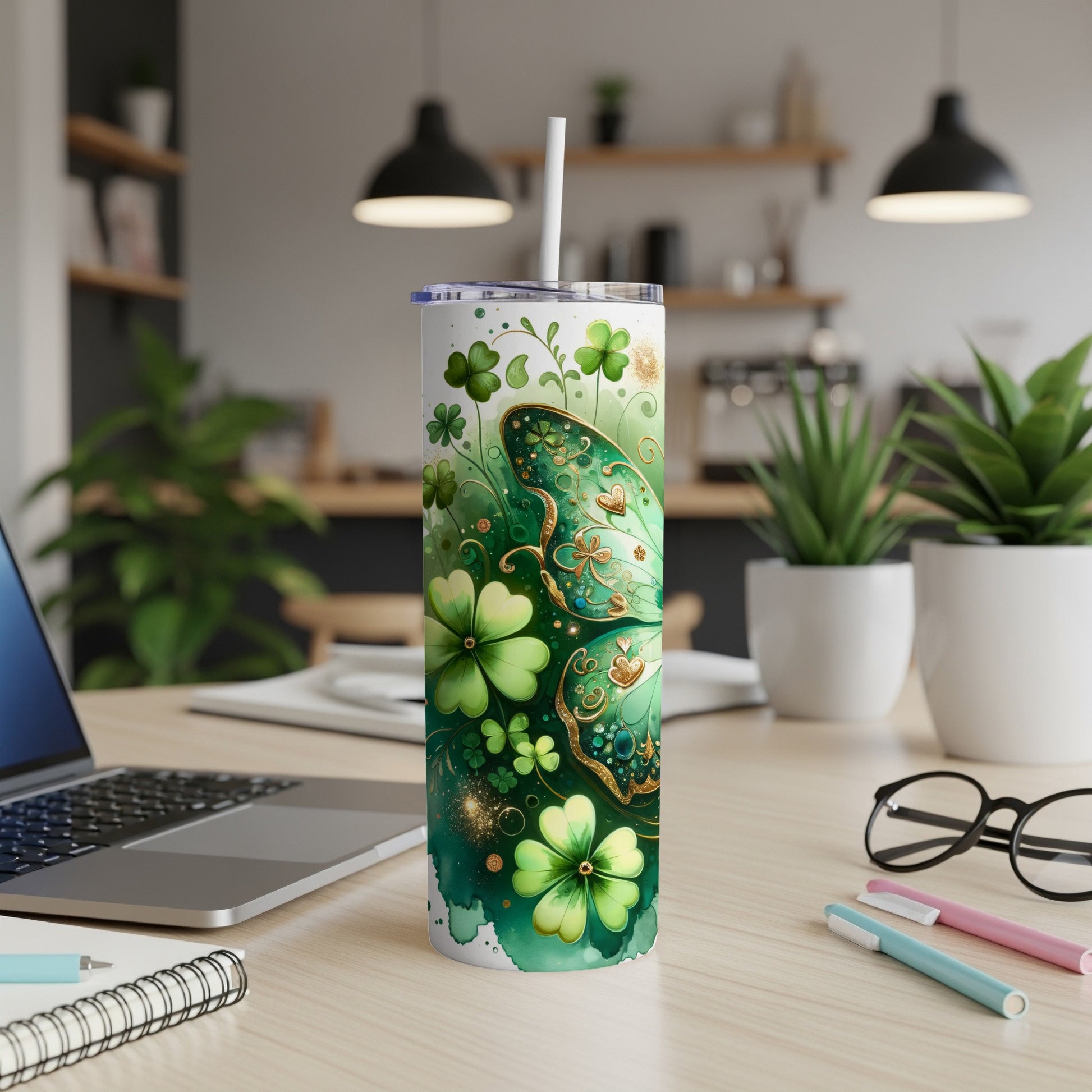 Green tumbler with shamrocks and butterfly, with straw, on a desk.