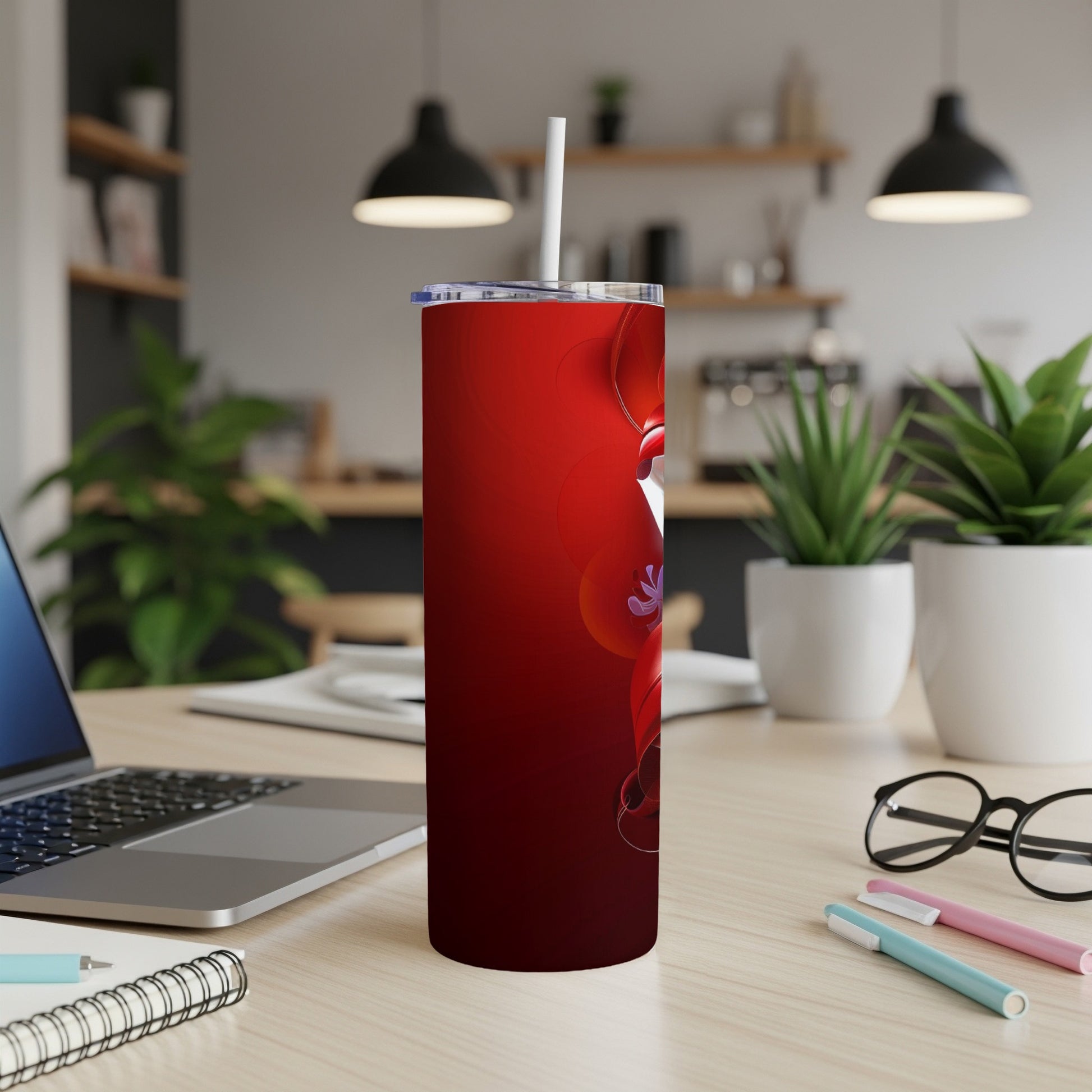 Red tumbler with white straw, sitting on a desk next to a laptop.