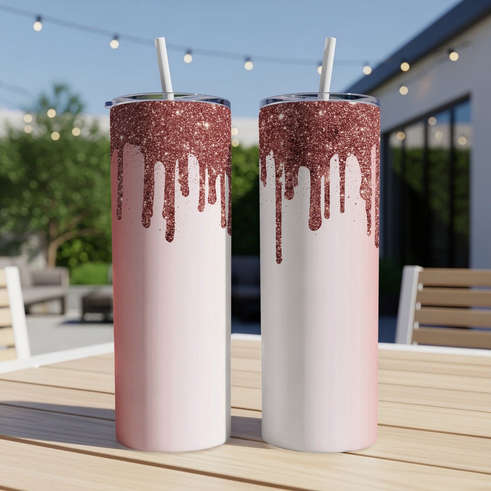Two rose gold glitter drip tumblers with white straws on a wooden table.