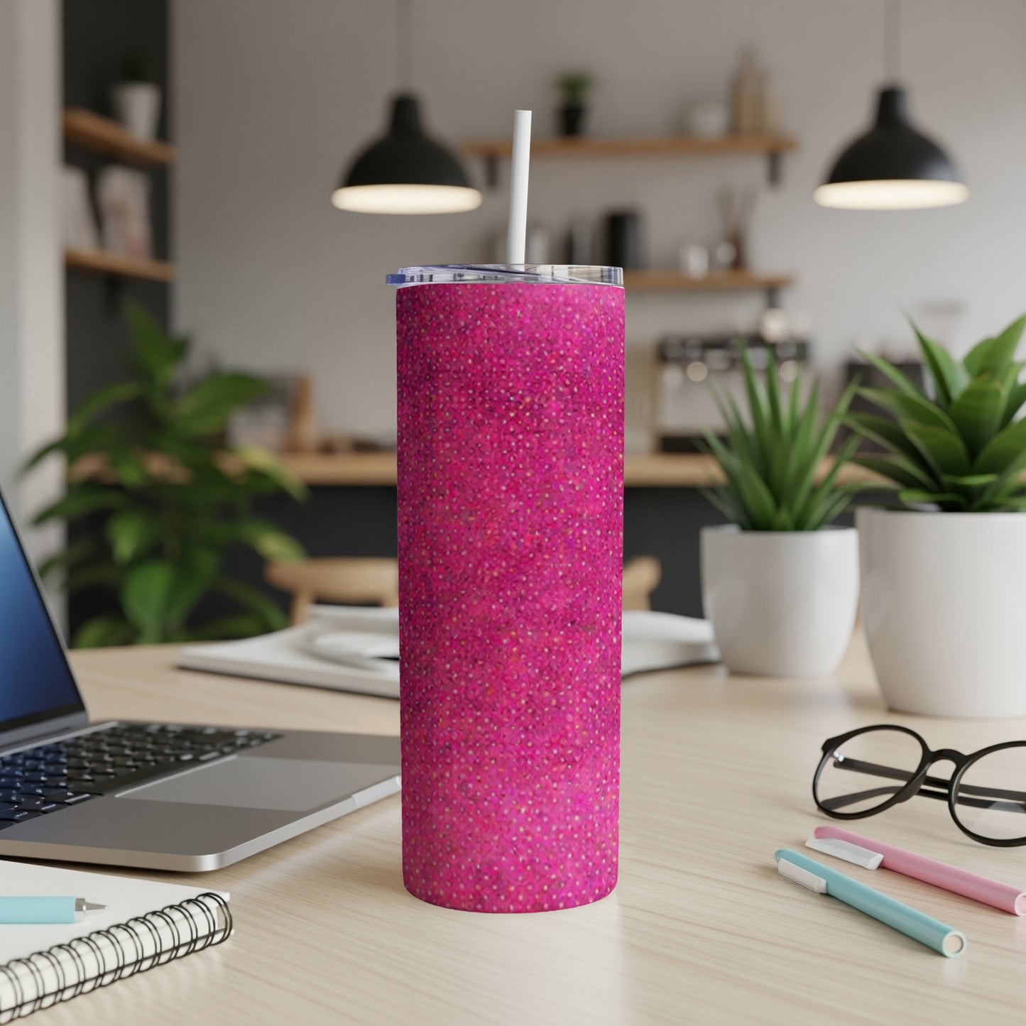 Pink glitter tumbler with straw on a desk with a laptop.