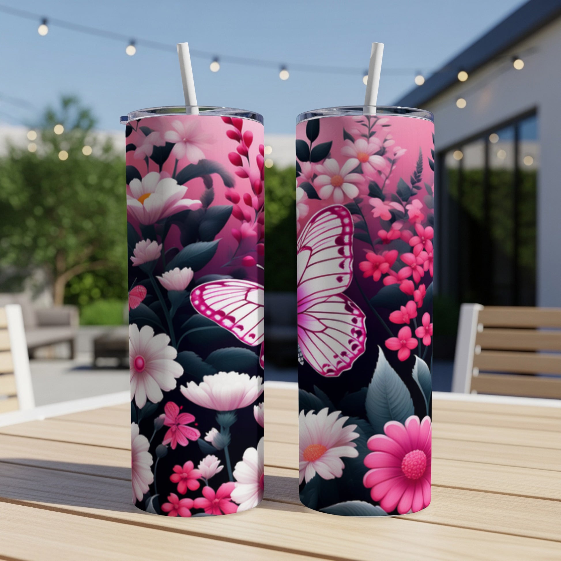 Two tumblers with pink floral and butterfly designs sit on a table outdoors.