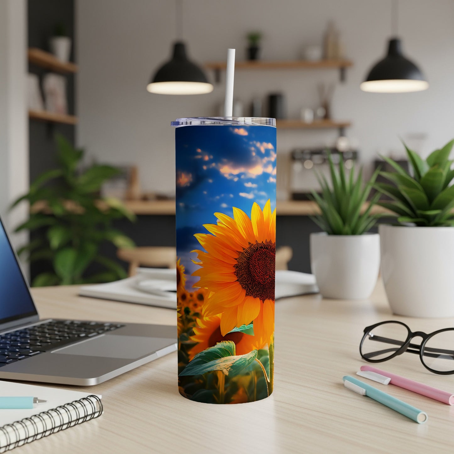 Sunflower tumbler with blue sky and clouds on a desk.