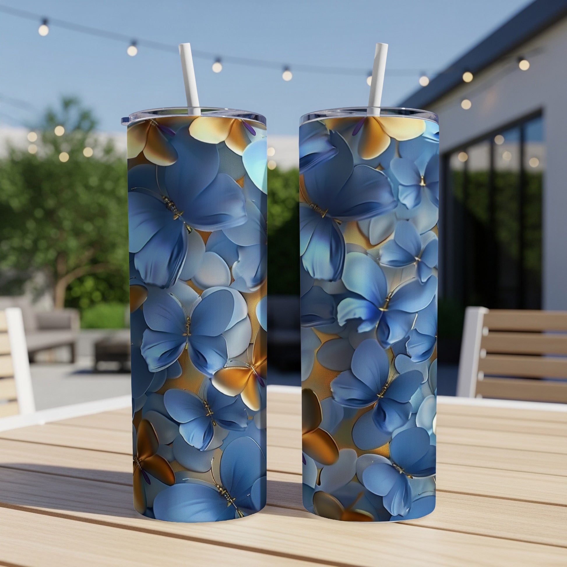 Two blue butterfly-patterned tumblers with straws on a wooden table.