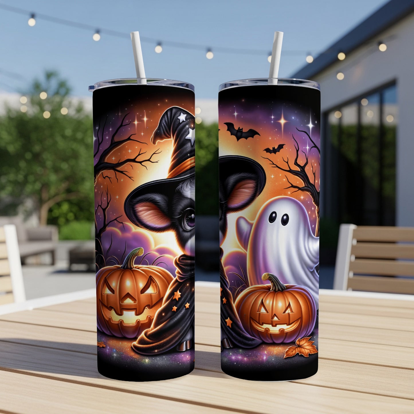 Two Halloween tumblers with a cow, ghost, and pumpkins on a table.