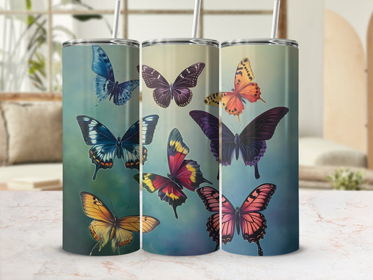 Three tumblers with colorful butterfly designs in a studio setting.