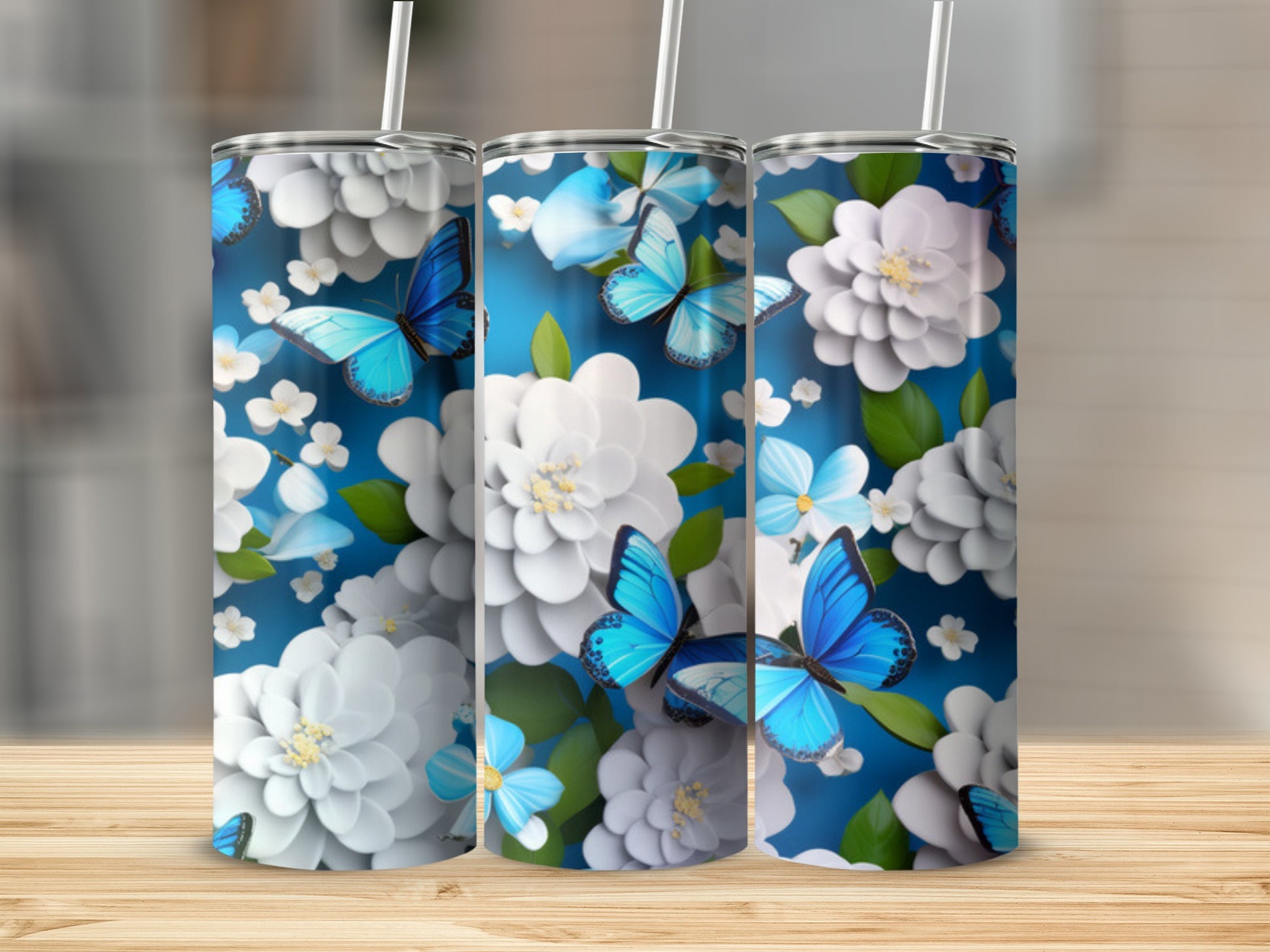 Three tumblers with blue butterflies and white flowers on a blue background.