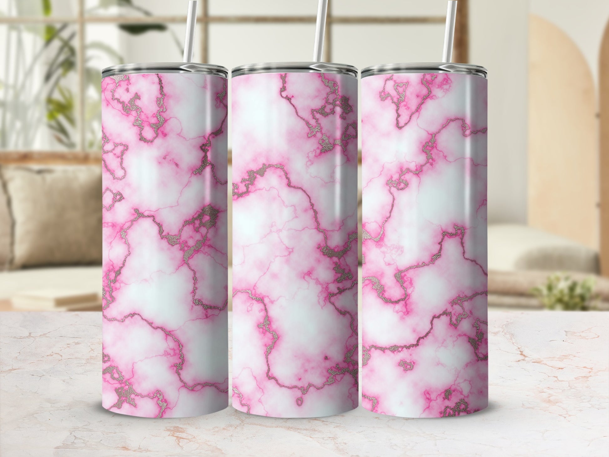Three pink and white marble tumblers with gold accents and straws.