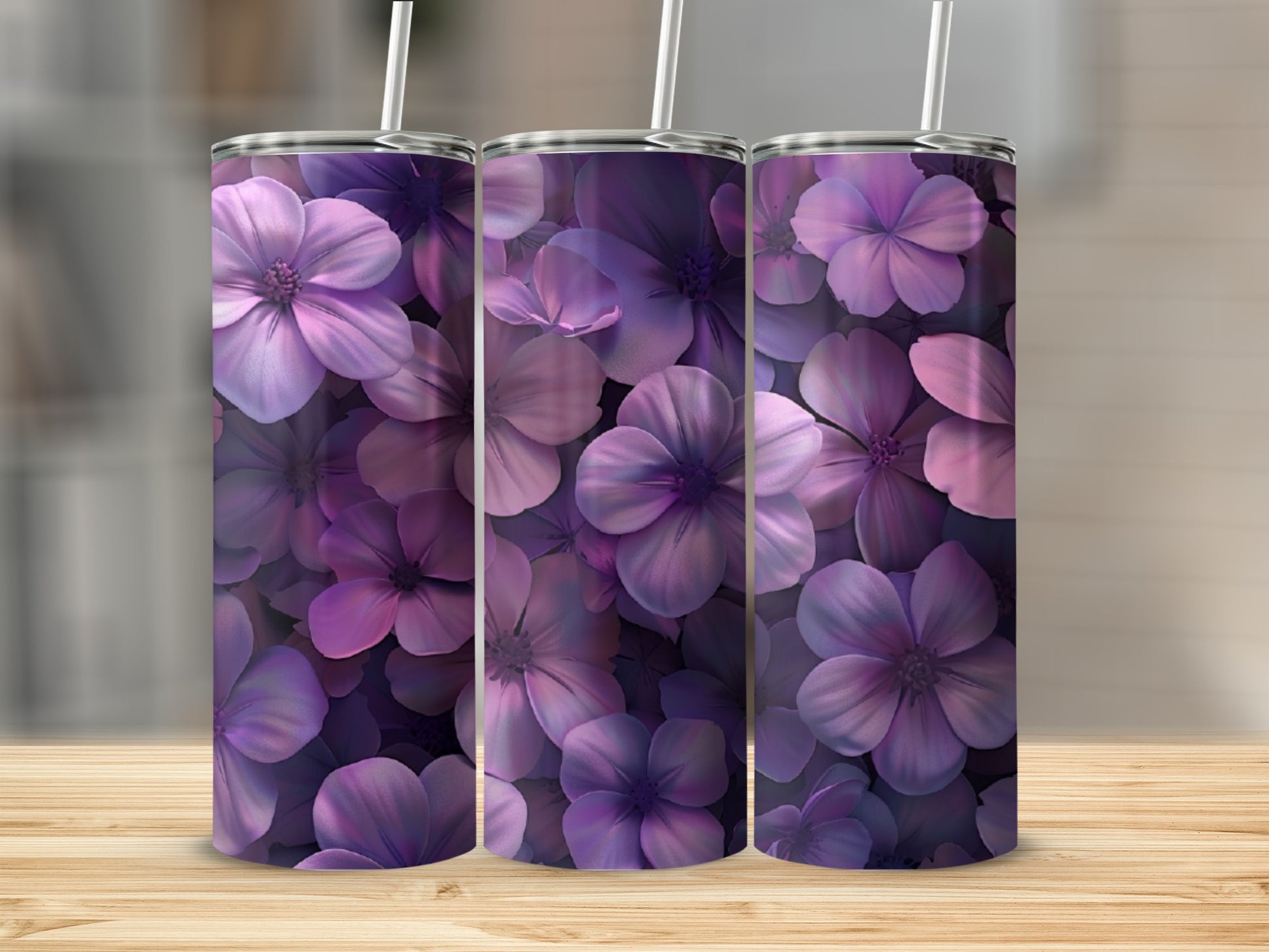 Three purple floral tumblers with straws, displayed on a wooden surface.