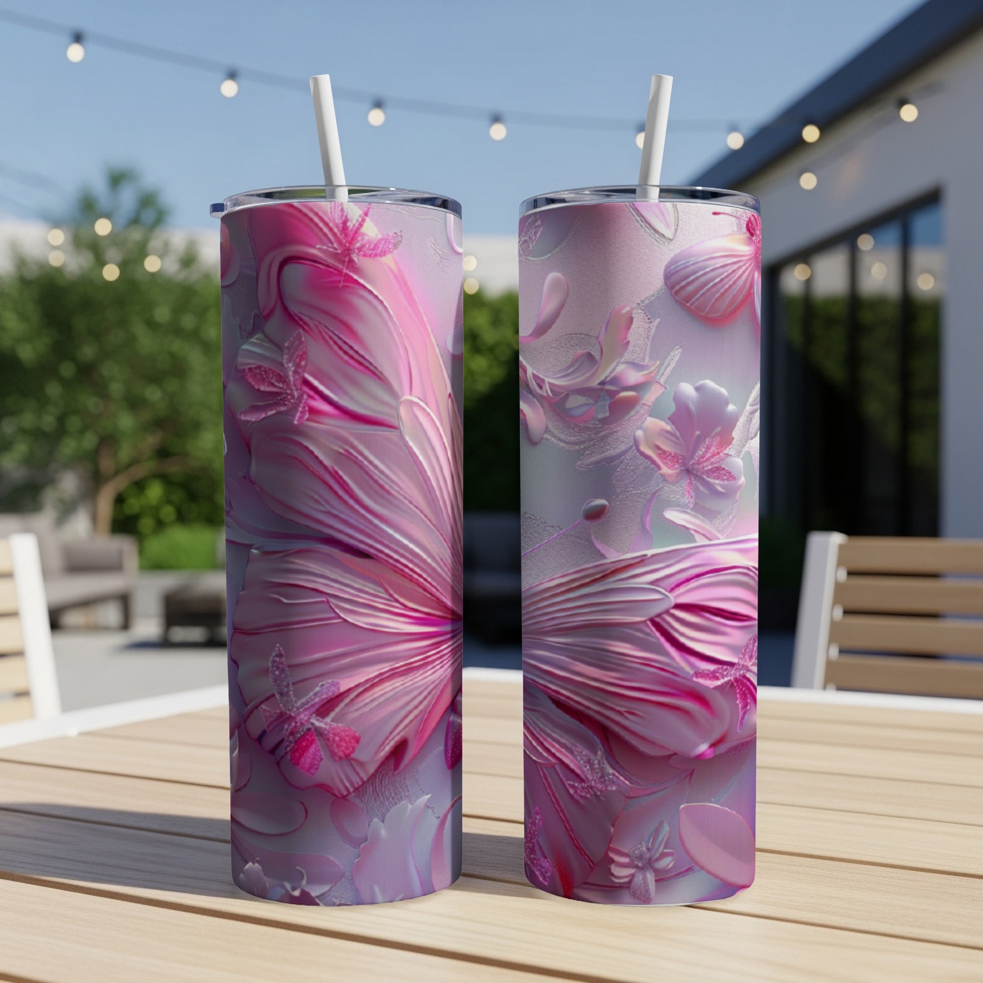 Two pink butterfly and floral design tumblers with straws on a table.