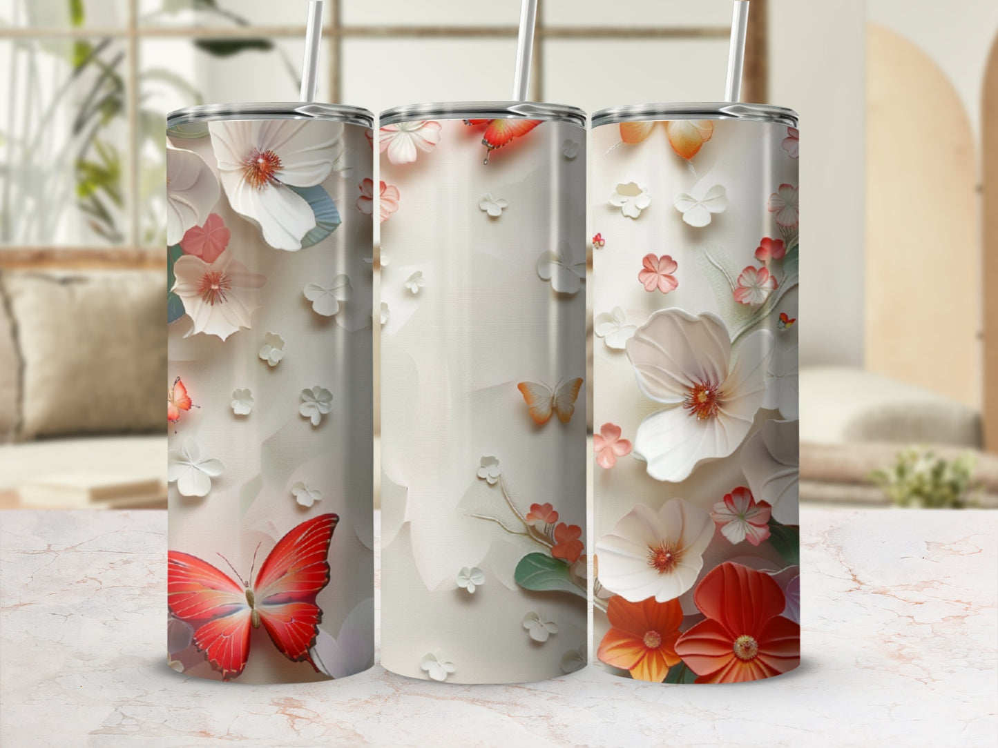 Three tumblers with floral and butterfly designs on a marble surface.