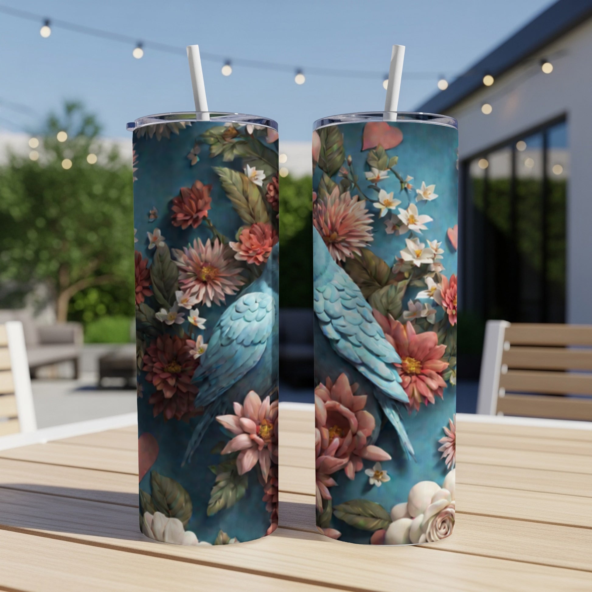 Two blue parrots sit among colorful flowers on a teal patterned skinny tumbler.