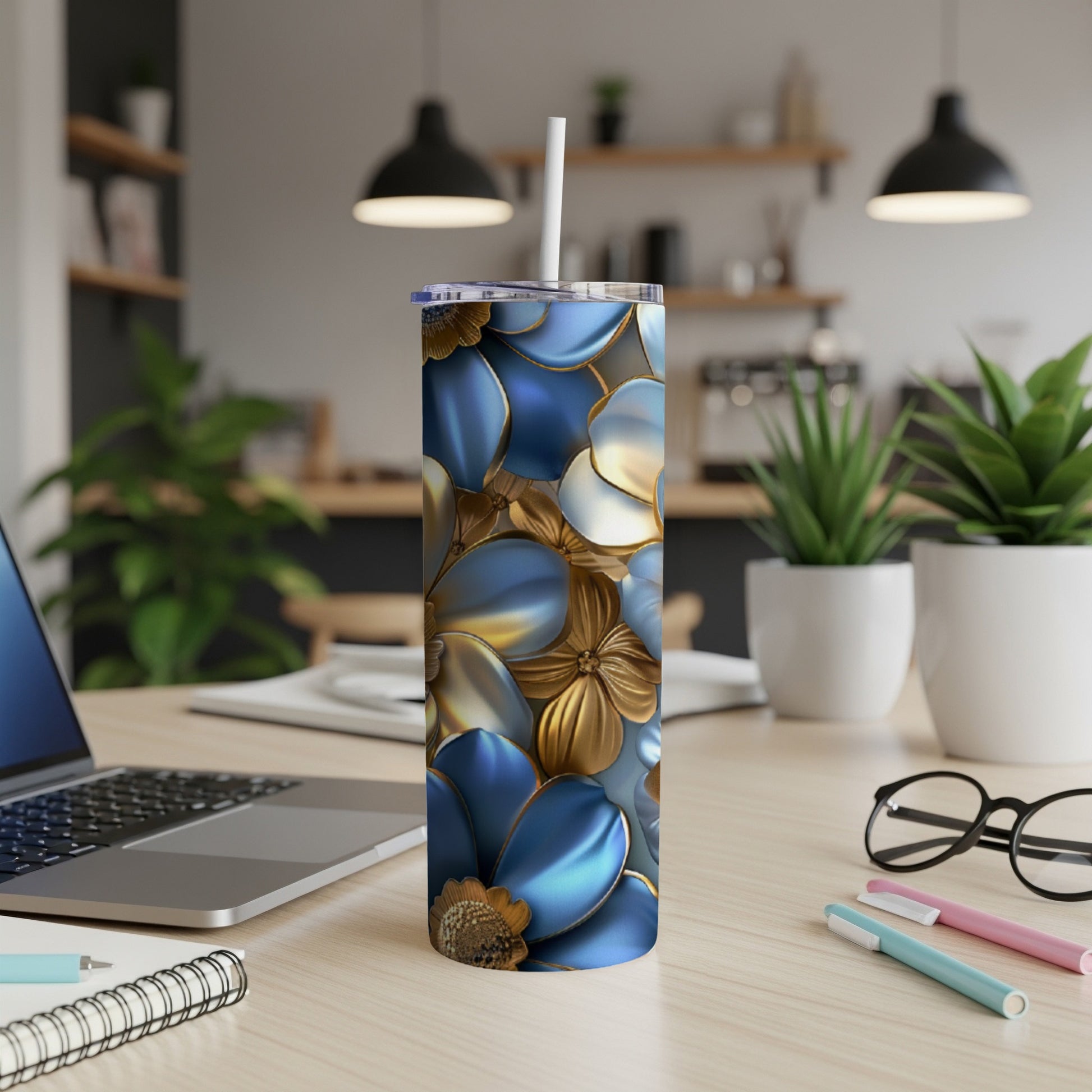 Blue and gold floral patterned tumbler on a desk with a laptop and pens.