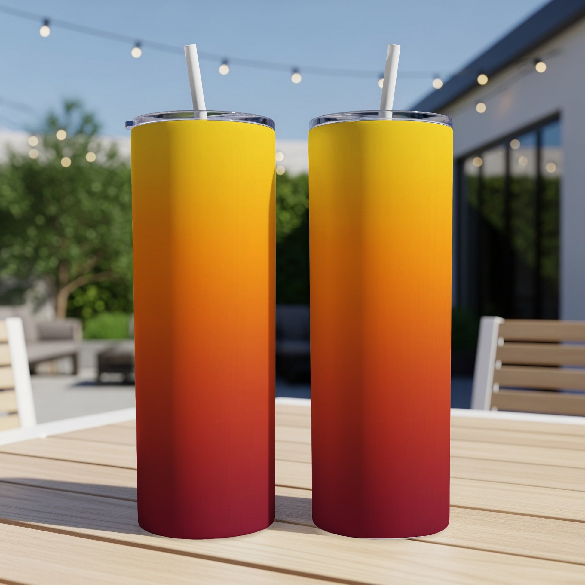Two tall tumblers with a sunset gradient design sit on a wooden table.