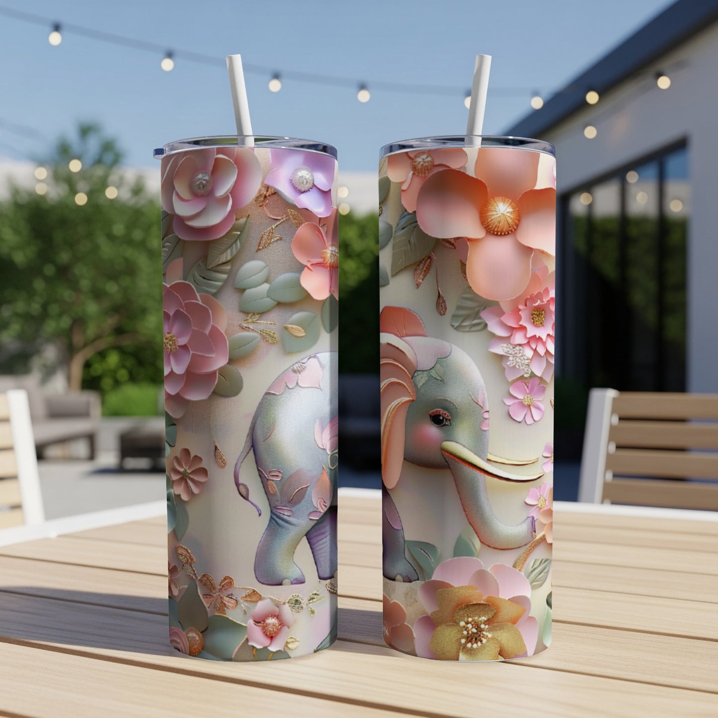 Pink floral elephant tumbler with straw on outdoor table.