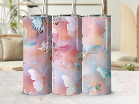 Three tumblers with pastel butterfly designs and straws, displayed on a marble surface.