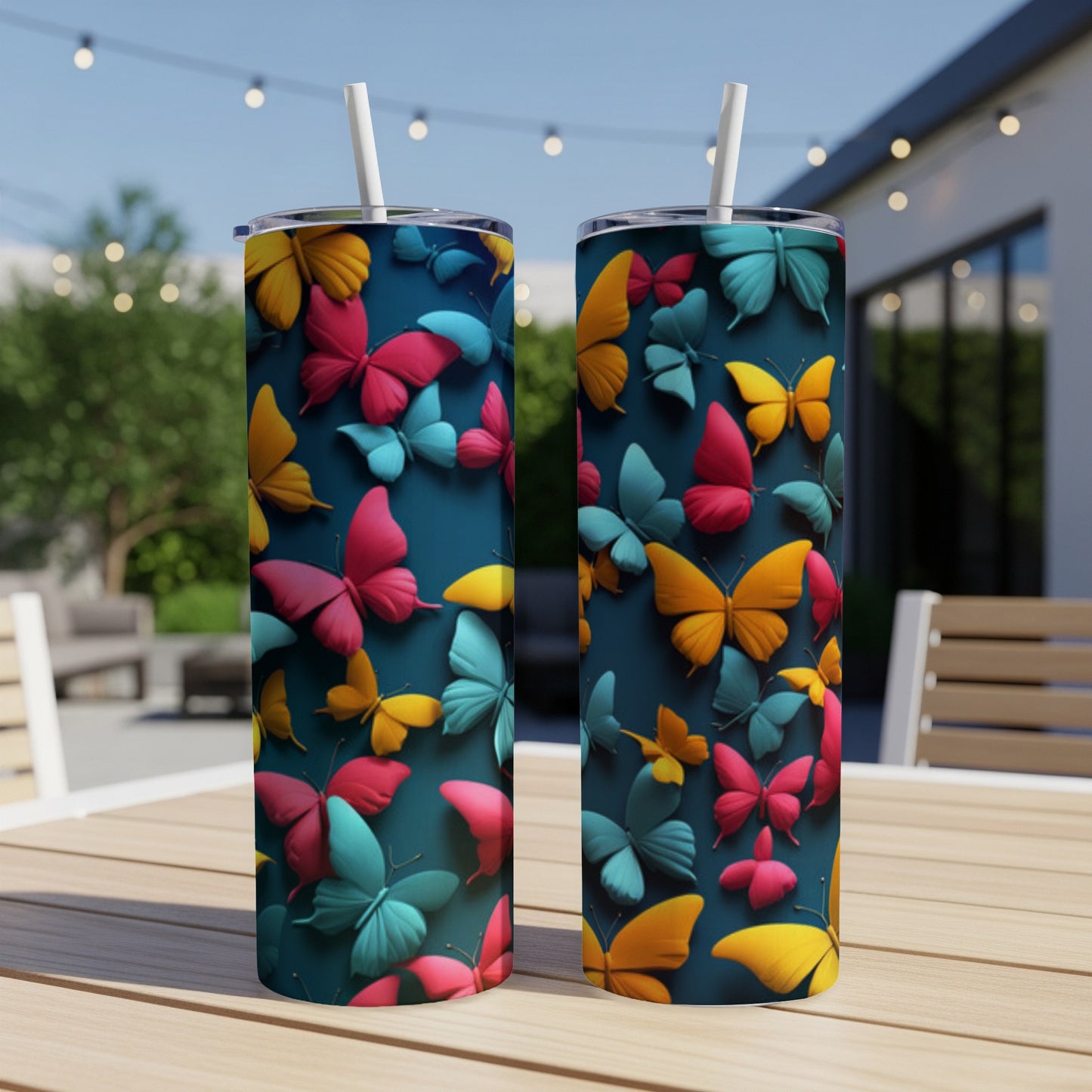 Two tumblers with colorful butterfly patterns on a patio table.