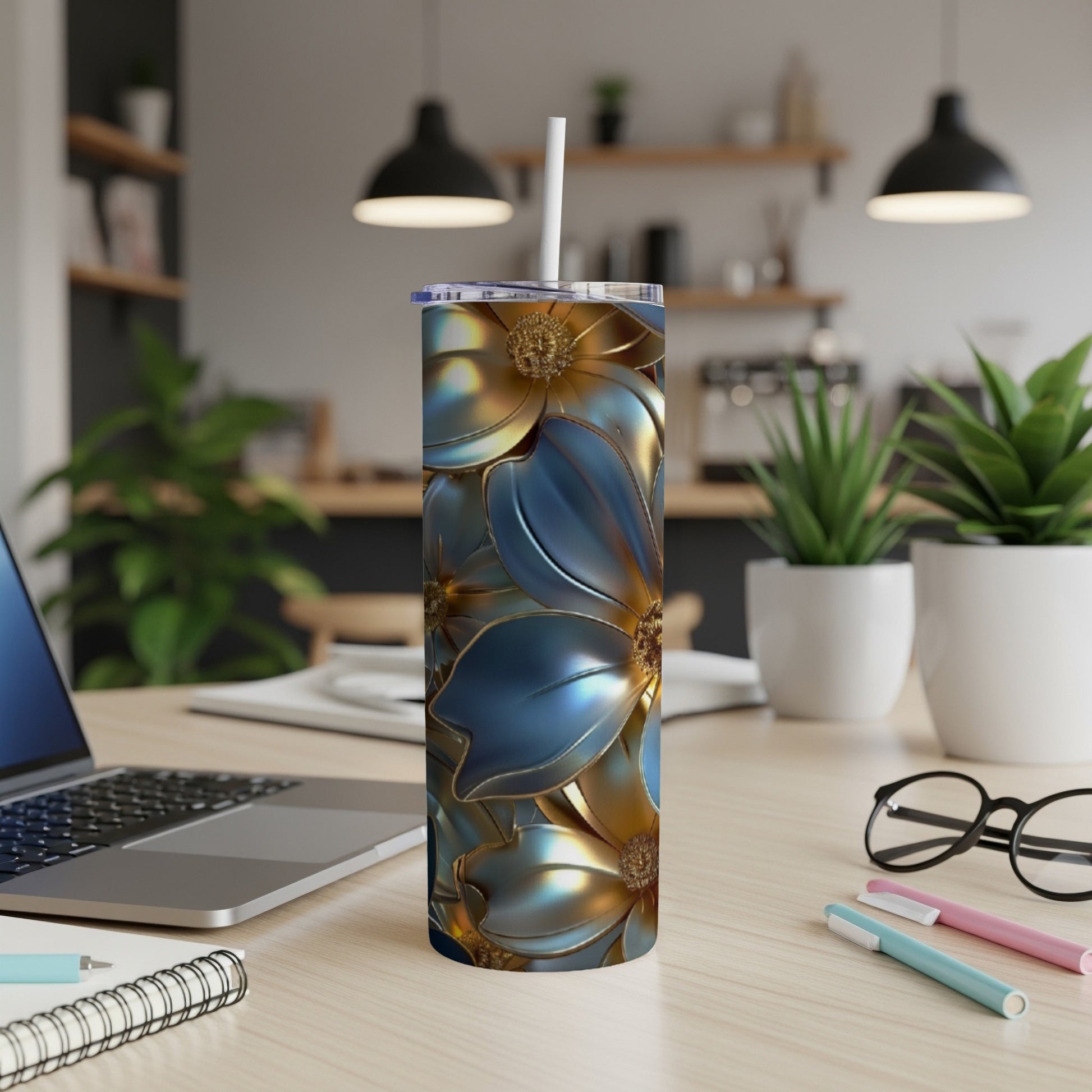 Gold and blue floral tumbler with straw on a desk.