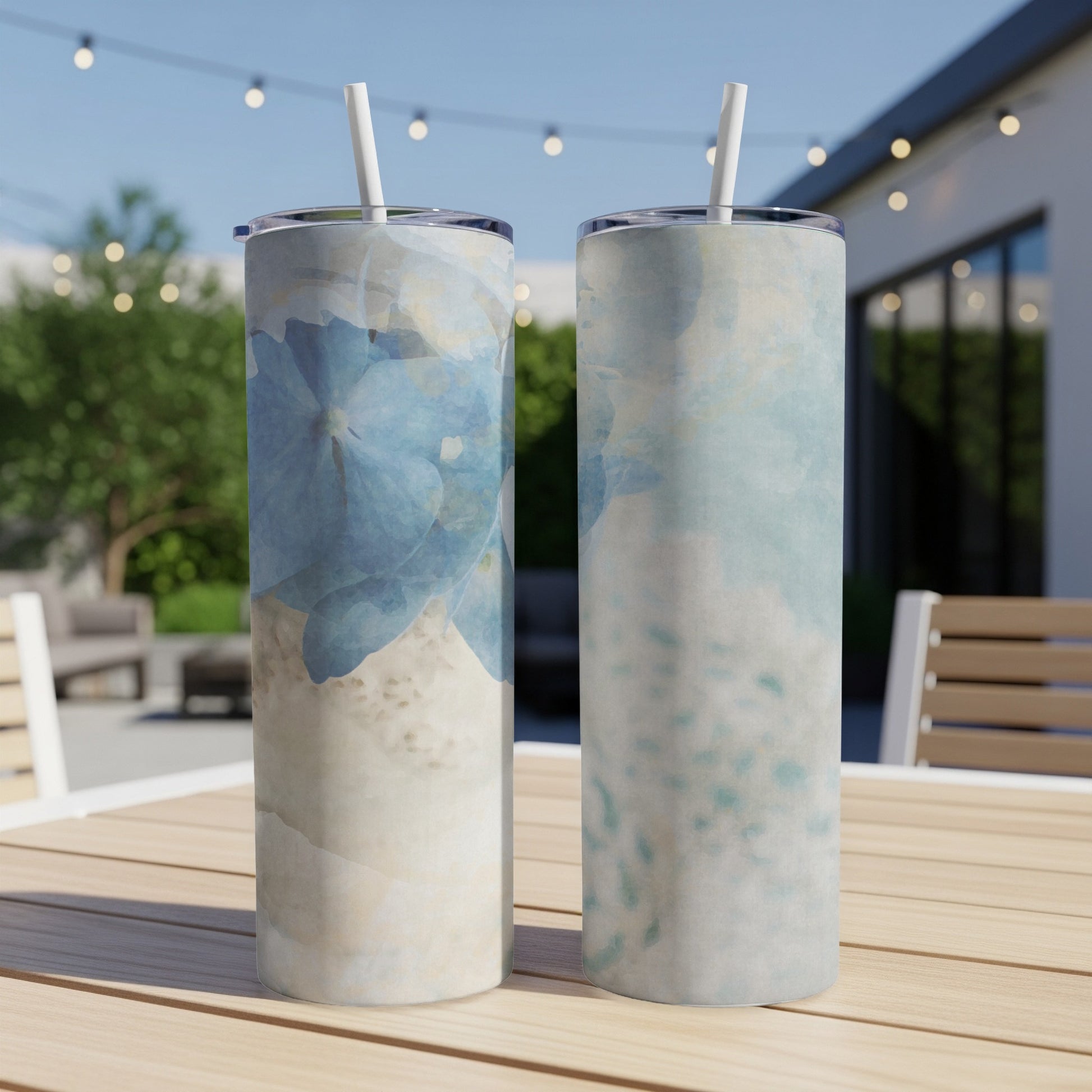 Two tall tumblers with blue floral abstract design on a table.