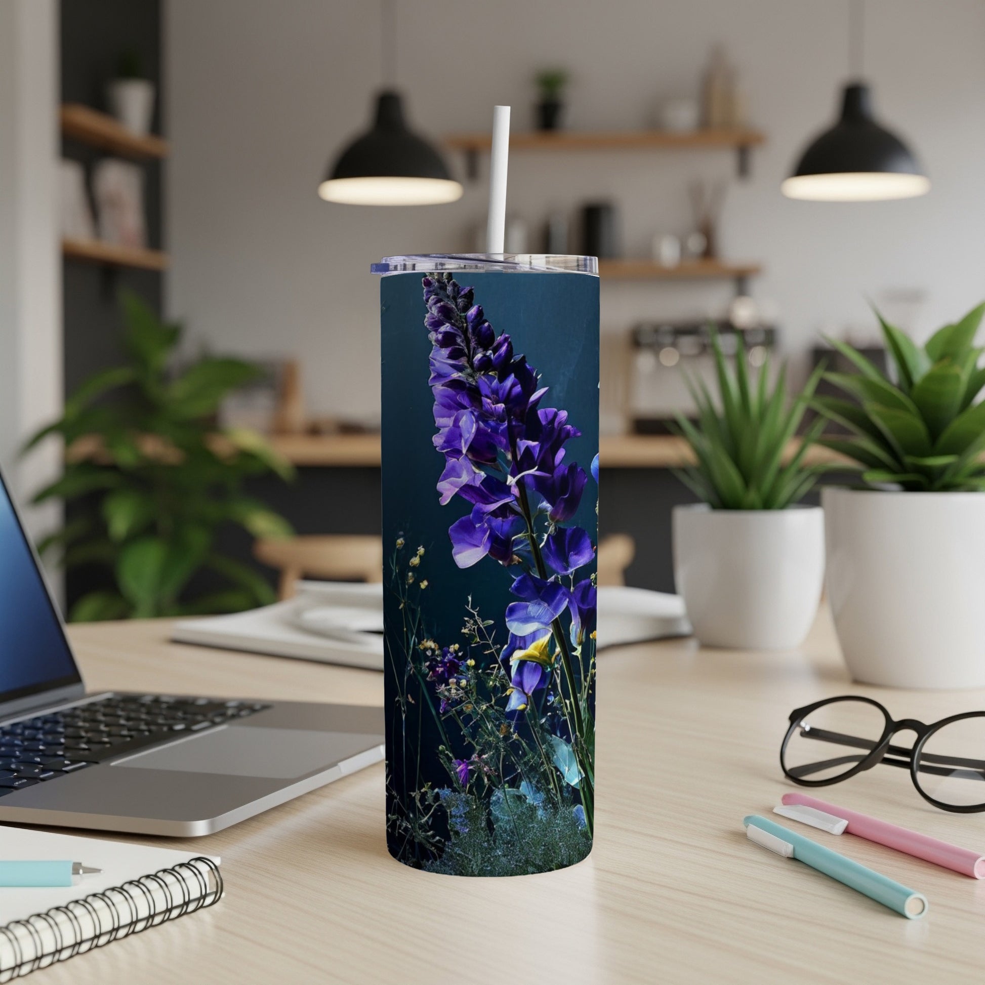 Tall tumbler with purple lupine flowers and greenery on a desk.