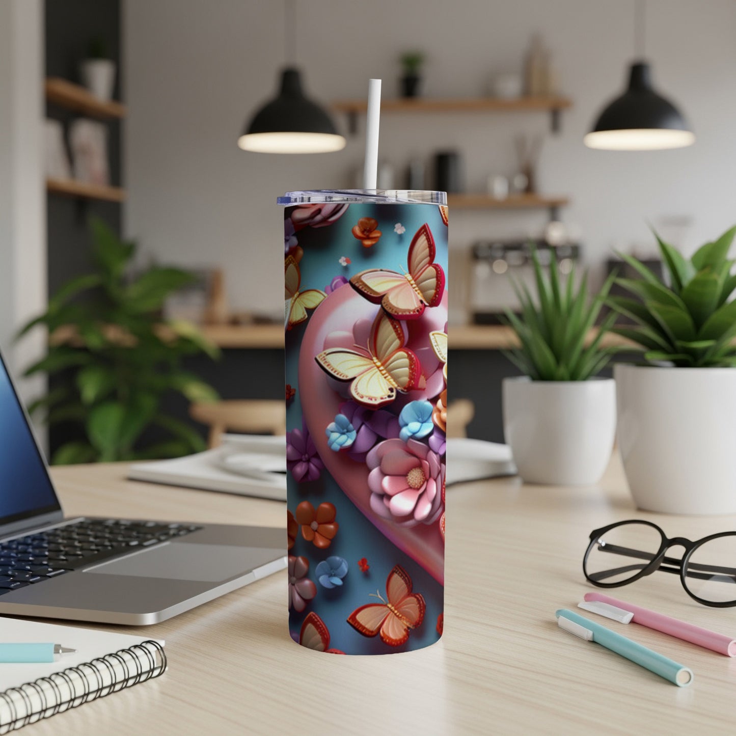Pink and blue floral tumbler with butterflies on a desk.