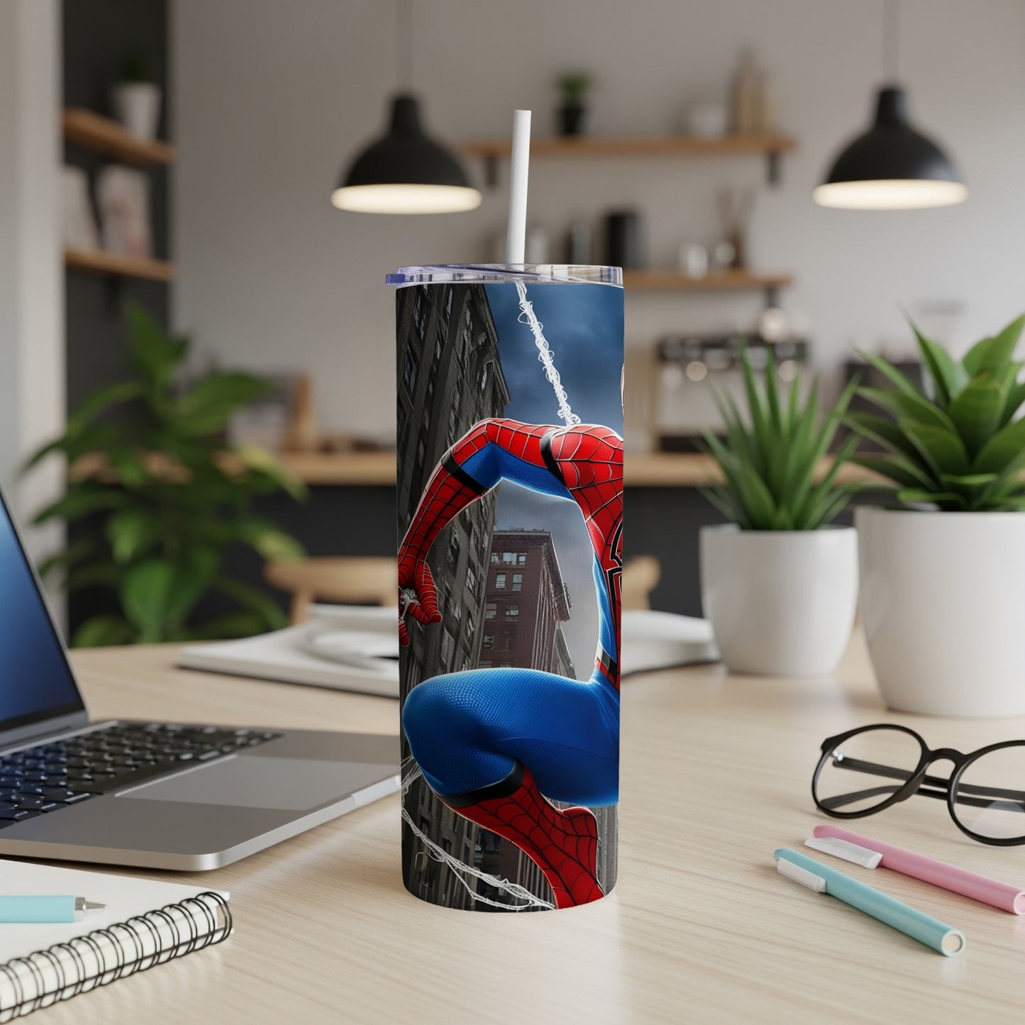 Spider-Man tumbler with web pattern on a desk next to a laptop.
