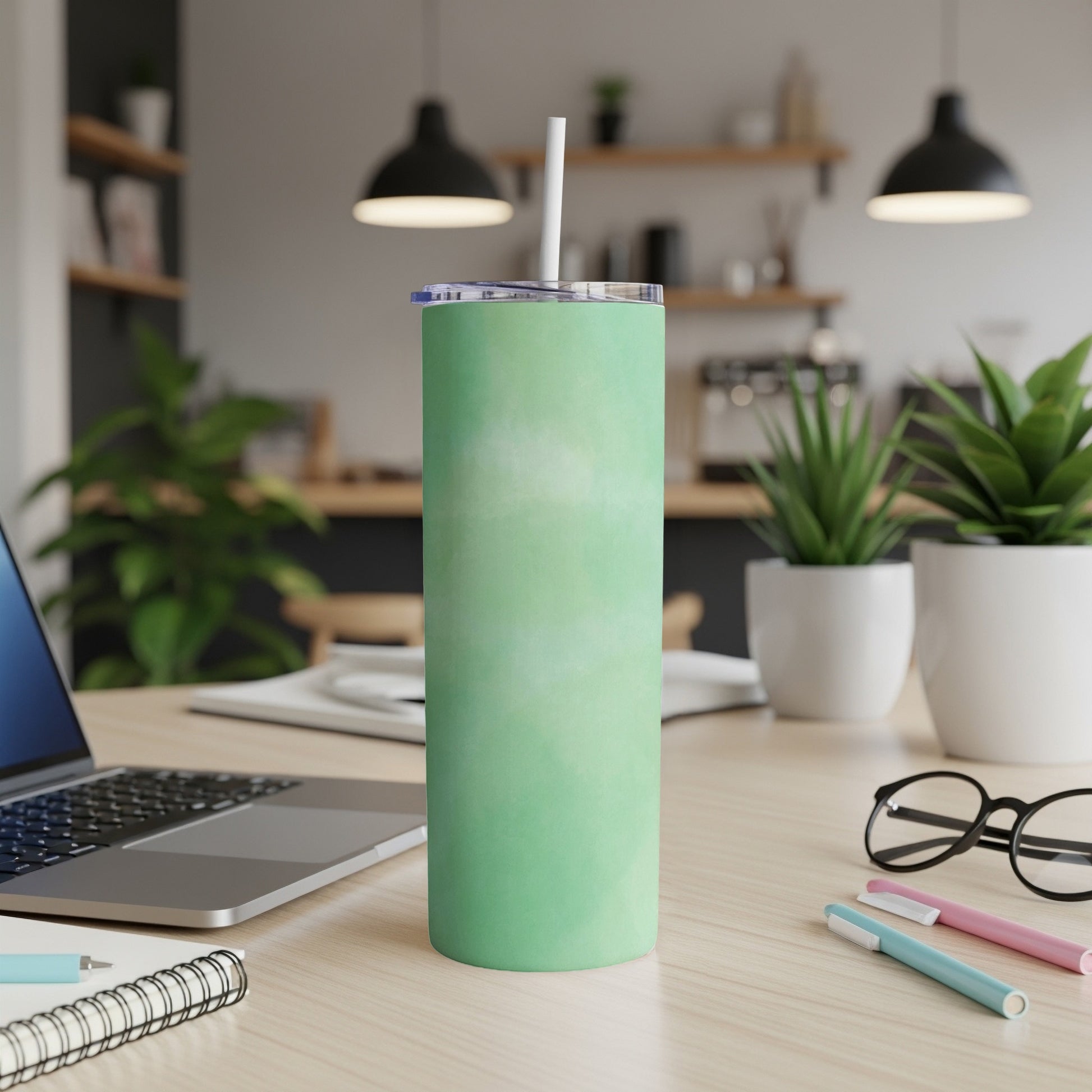 Green marbled tumbler with white straw on a desk.