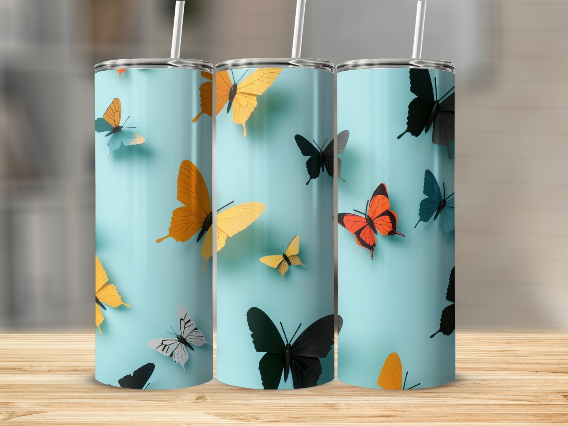 Three tumblers with butterfly designs on a light blue background.