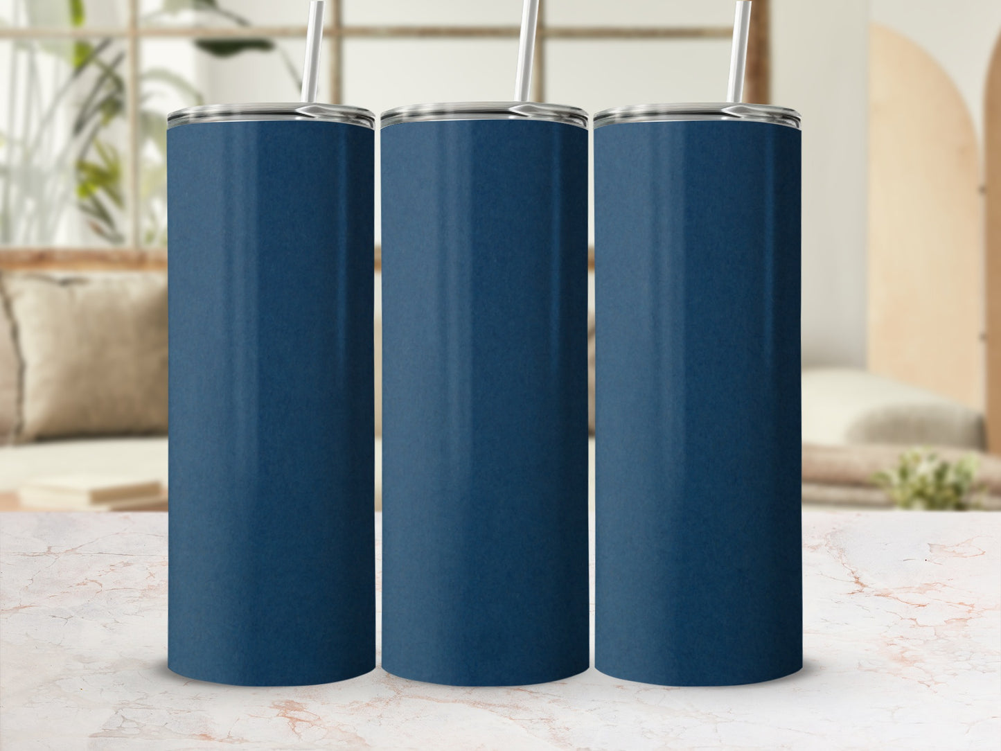 Three plain navy blue tumblers with straws on a marble surface.