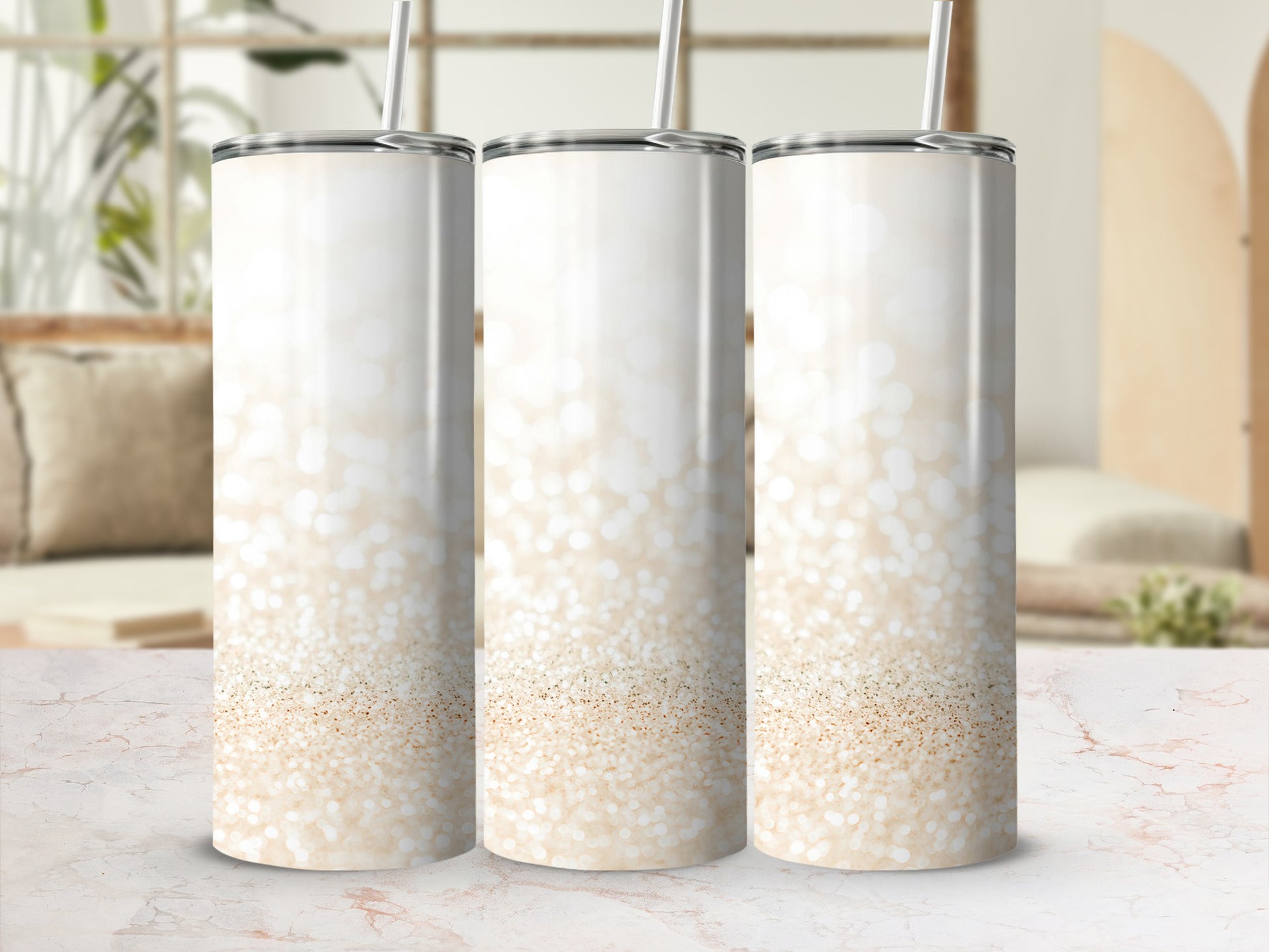 Three tall, glitter-covered tumblers with straws on a marble surface.