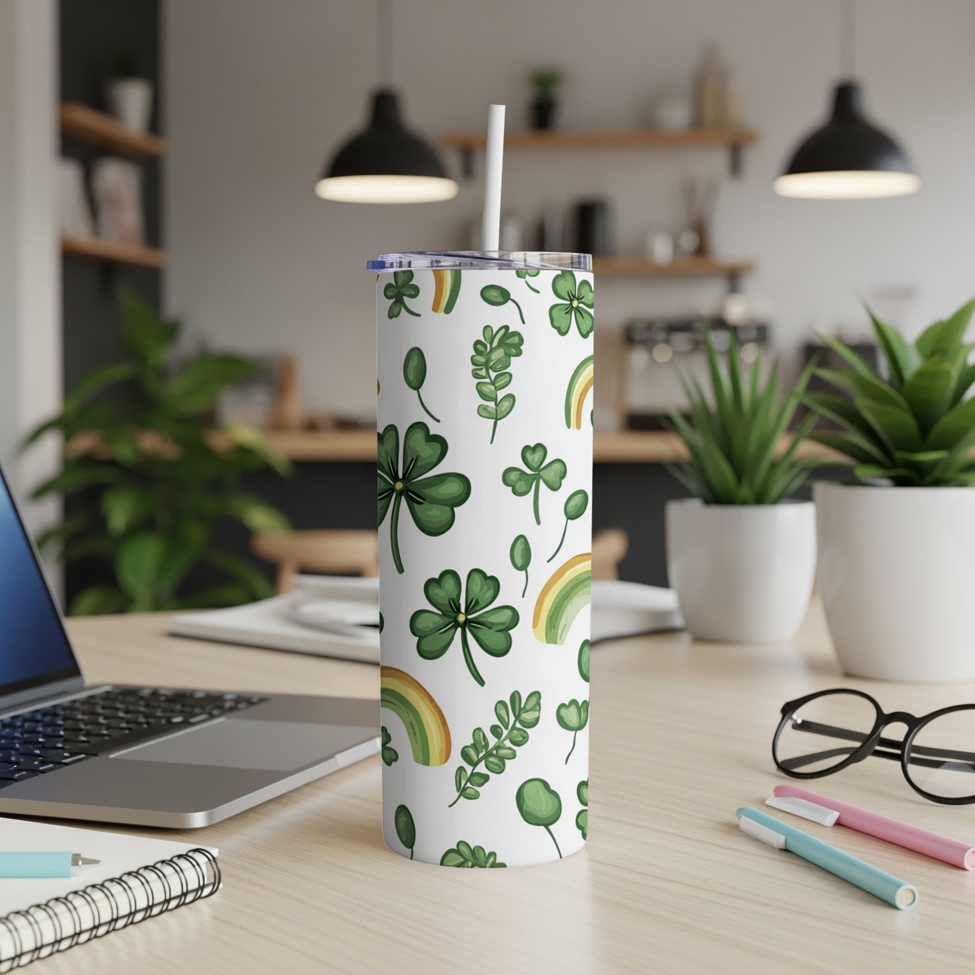 White tumbler with shamrocks and rainbows, straw inserted, on desk.