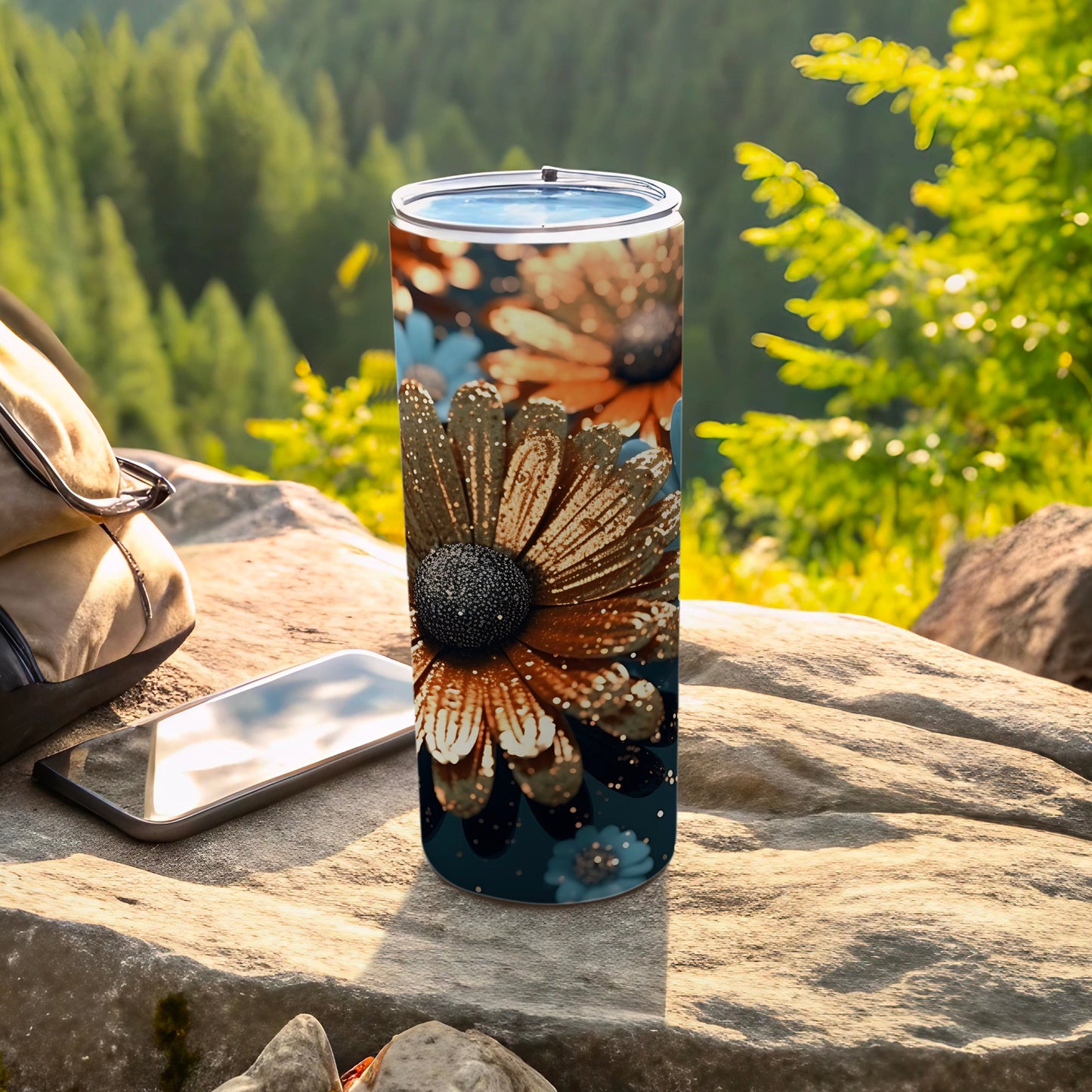 Tall tumbler with floral pattern, resting on rocks near a backpack and phone.