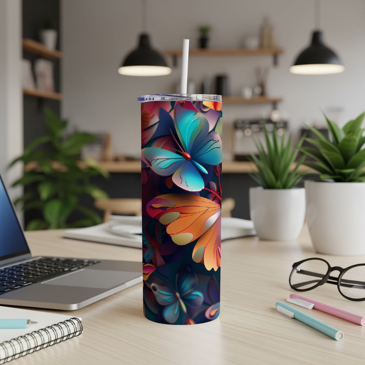 Floral patterned tumbler with butterflies and leaves on a desk.