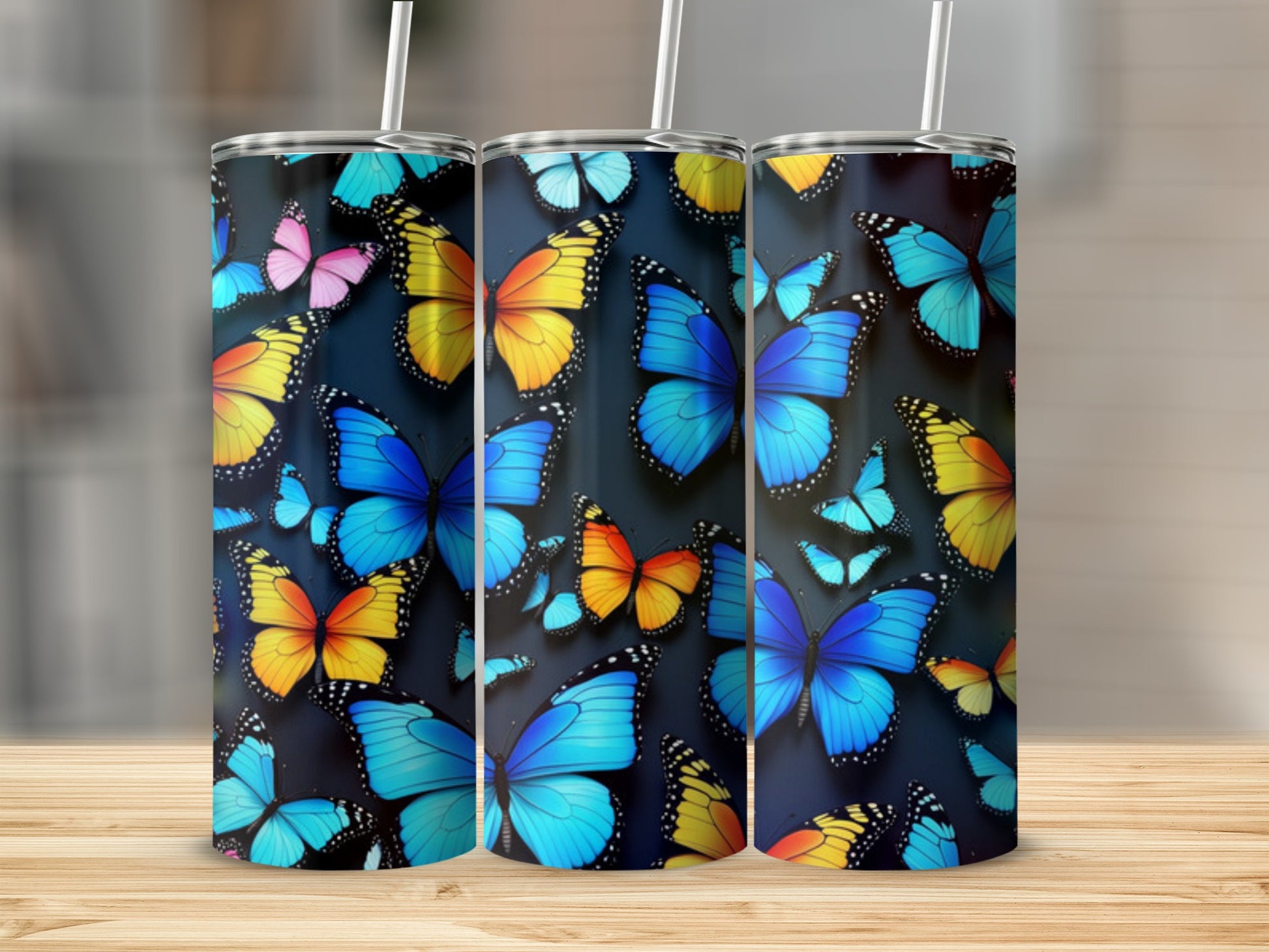 Three tumblers with a colorful butterfly pattern on a wooden surface.