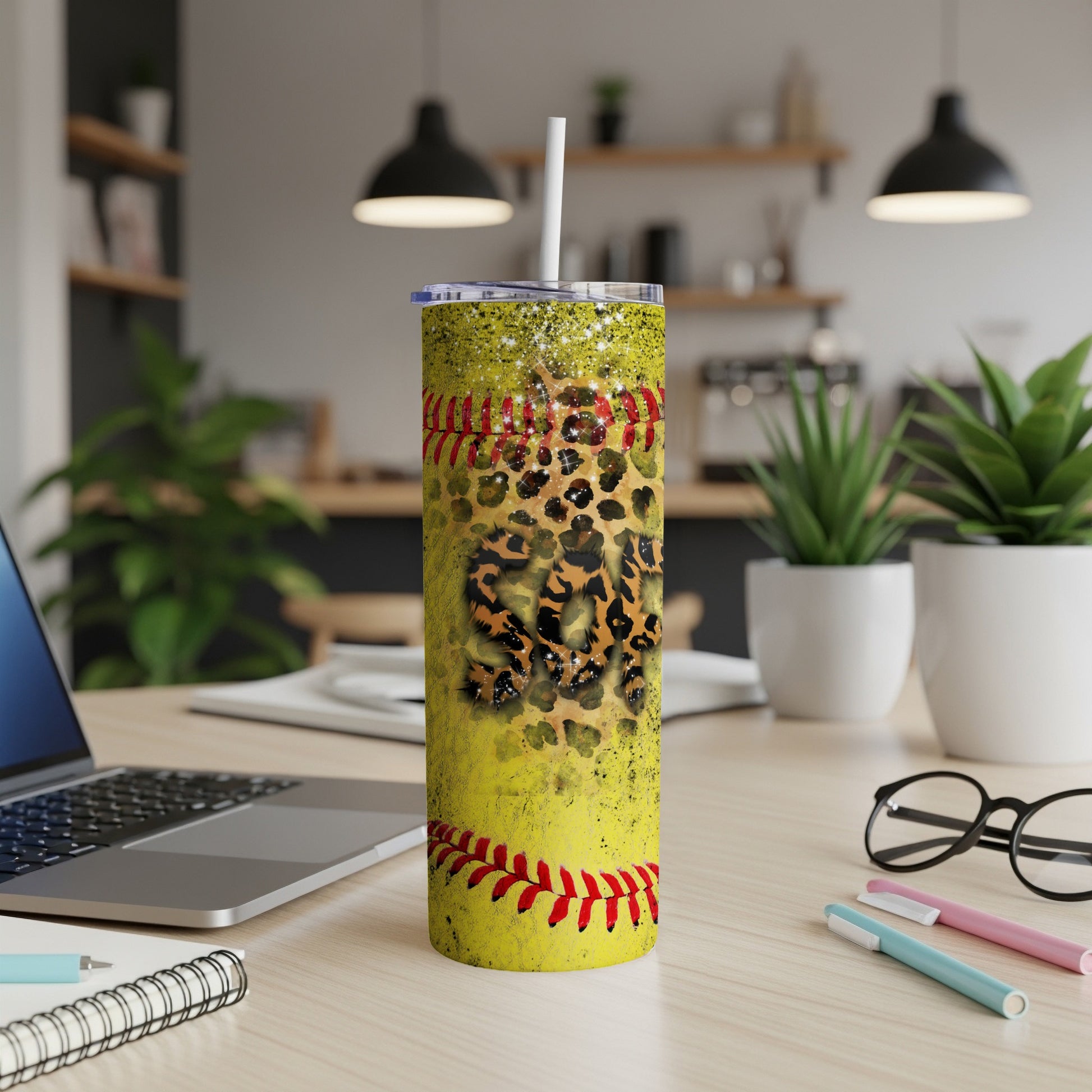 Yellow tumbler with baseball and leopard print, on a desk.