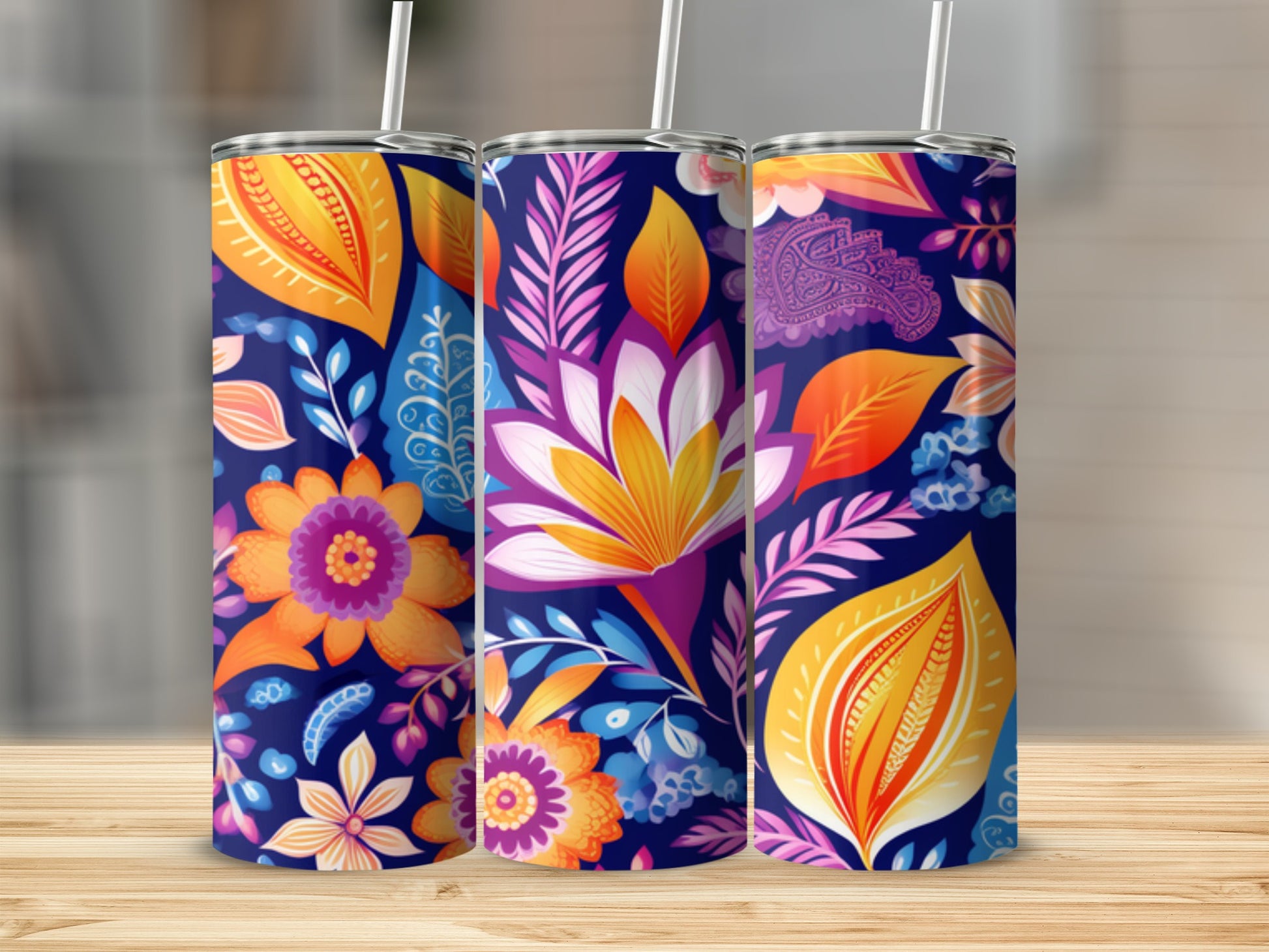 Three tumblers with vibrant floral and paisley patterns on a wooden surface.
